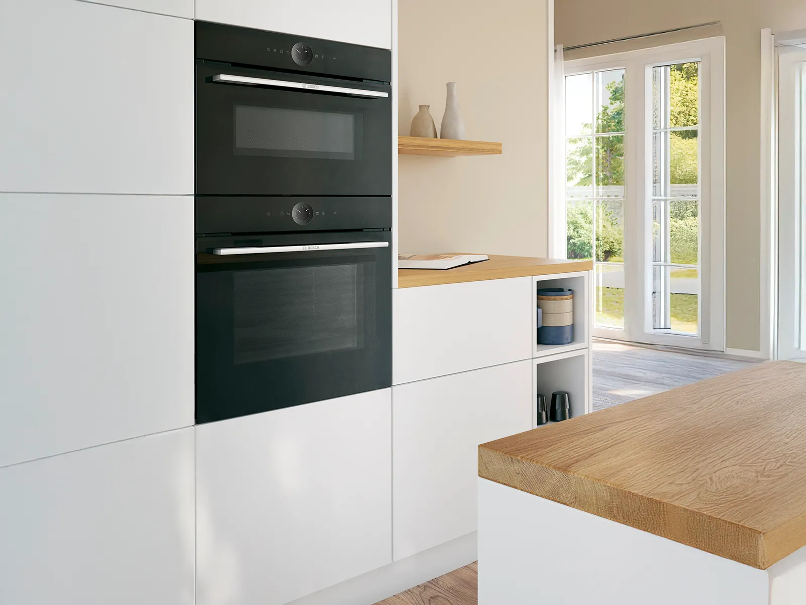 Bucătărie Bosch cu cuptoare negre suprapuse, încorporate în dulapuri albe, lângă o fereastră.