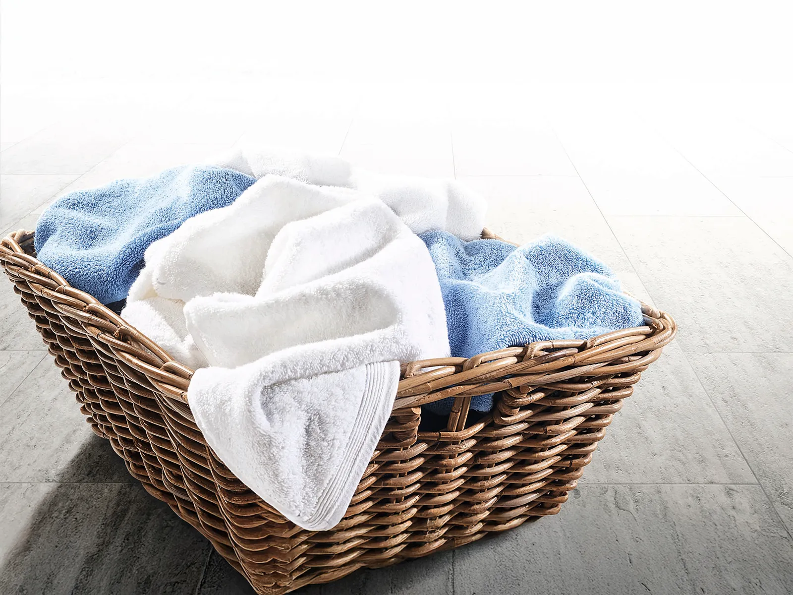 A laundry basket filled to the brim with dirty towels.