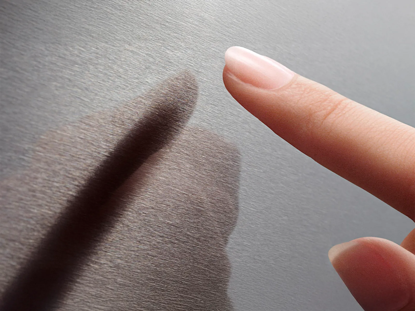 A fingertip about to touch its shadow on a textured grey surface.