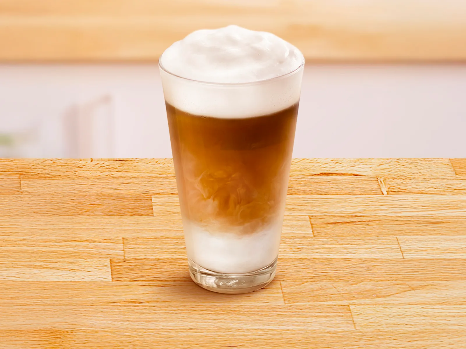 Tazza di vetro con un latte macchiato.