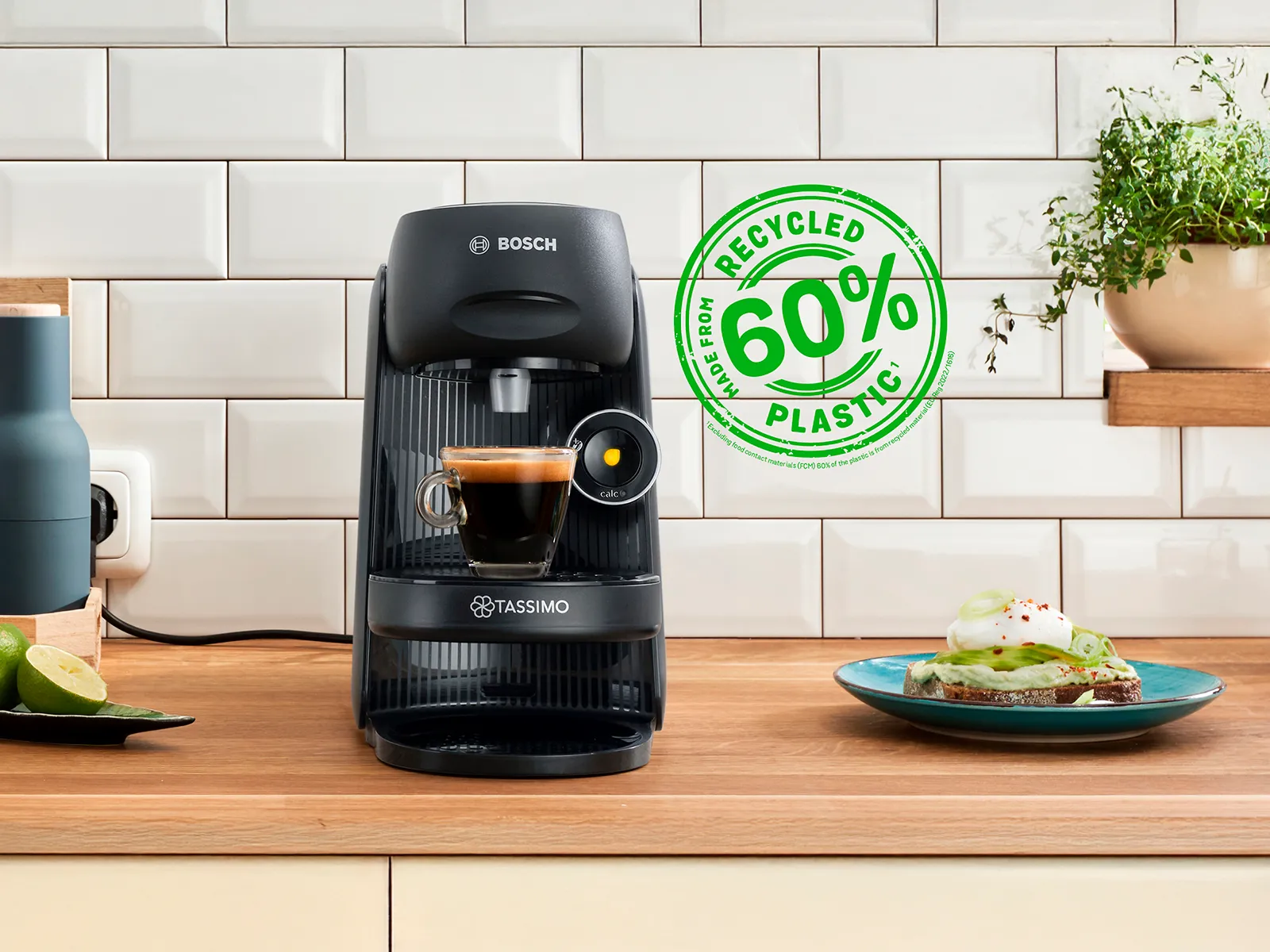 The TASSIMO FINESSE friendly on a kitchen worktop with a filled expresso cup. Next, a sign for 60% recycled plastic.