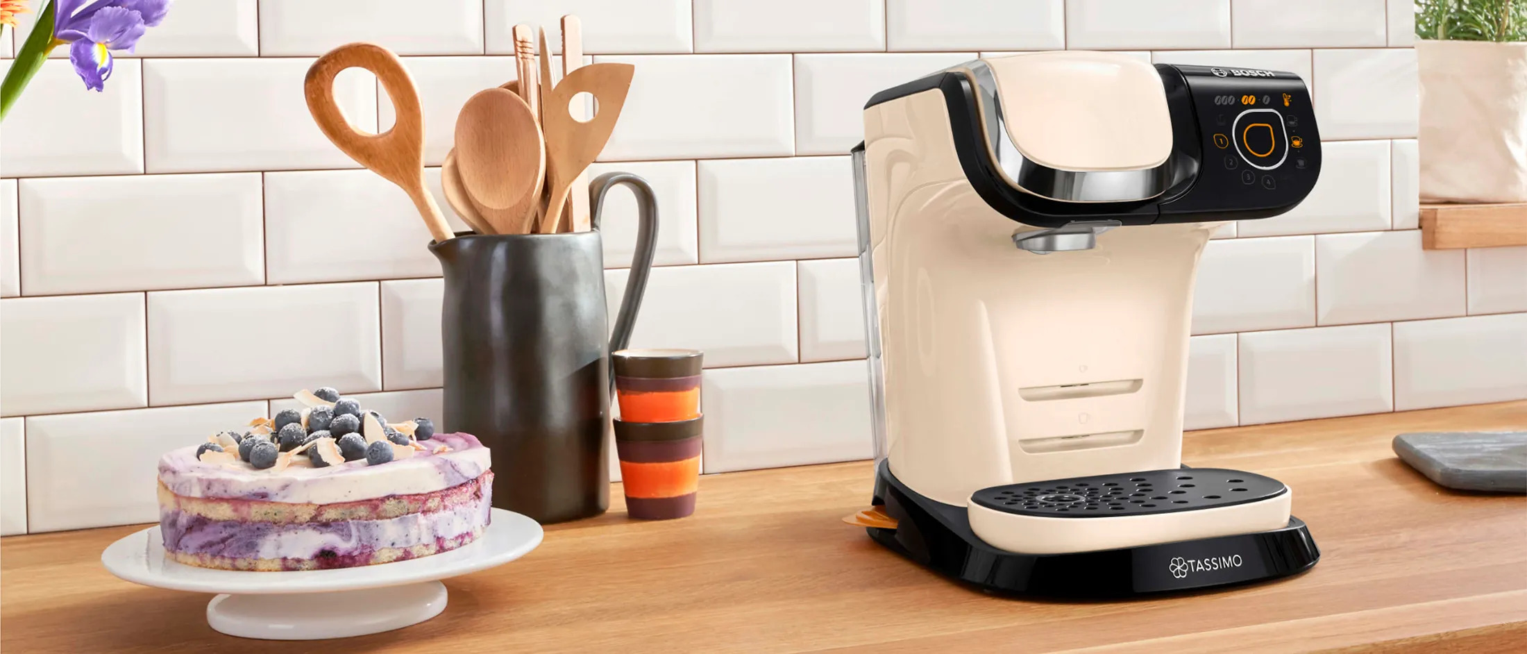 The TASSIMO coffee machine MYWAY 2 standing with a Latte Macchiato on a kitchen worktop.