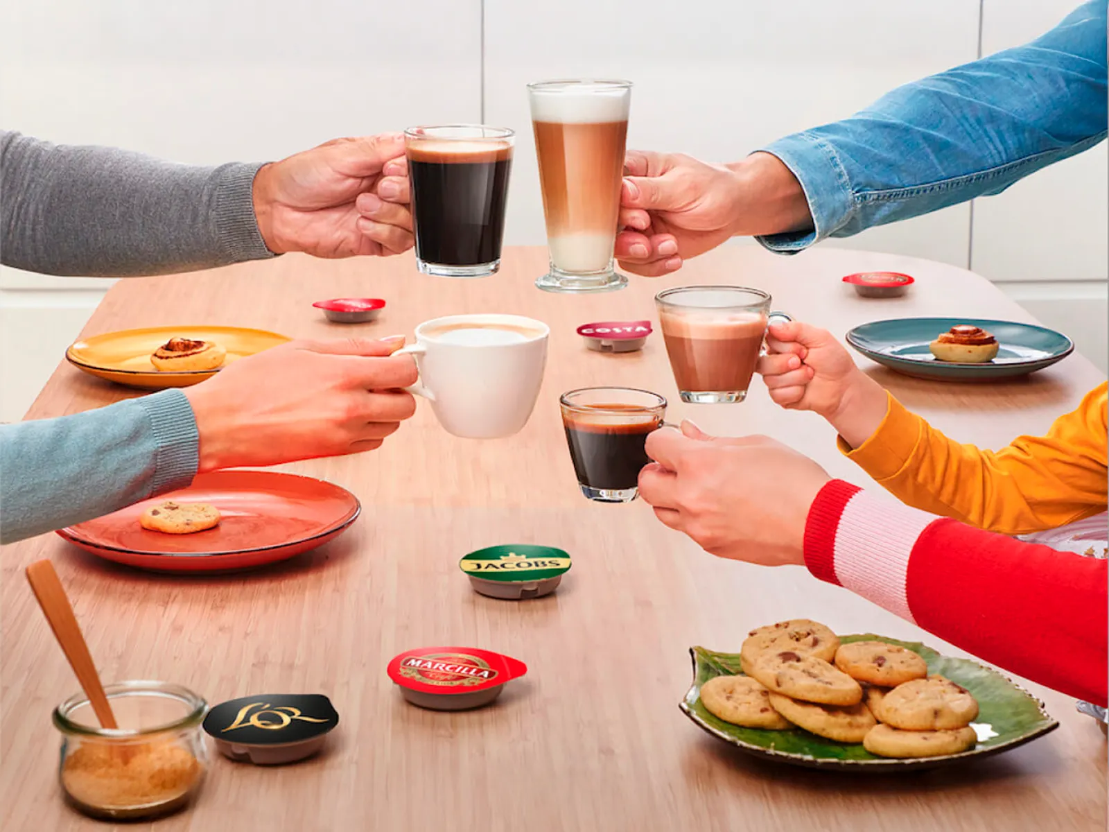 Persone che brindano con bevande diverse preparate con la macchina da caffè TASSIMO.