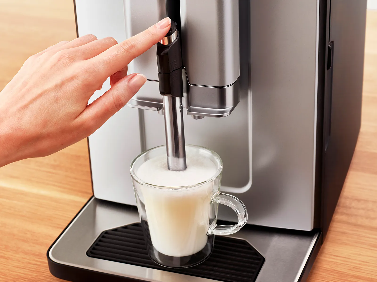 Index finger pressing down Series 2 VeroCafe frother lever.
