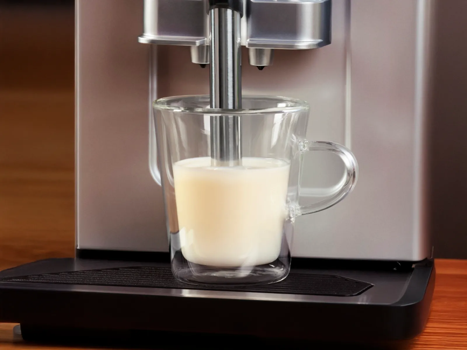 1 cup filled with milk with frother pushed down, on Series 2 VeroCafe machine drip tray.