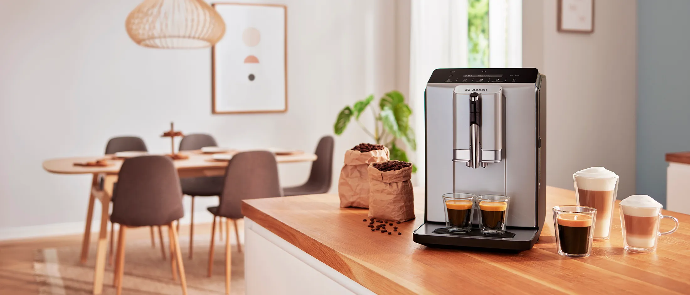 Filiżanki różnych kaw, od espresso po caffe latte, obok automatyczny ekspres do kawy natle salonu