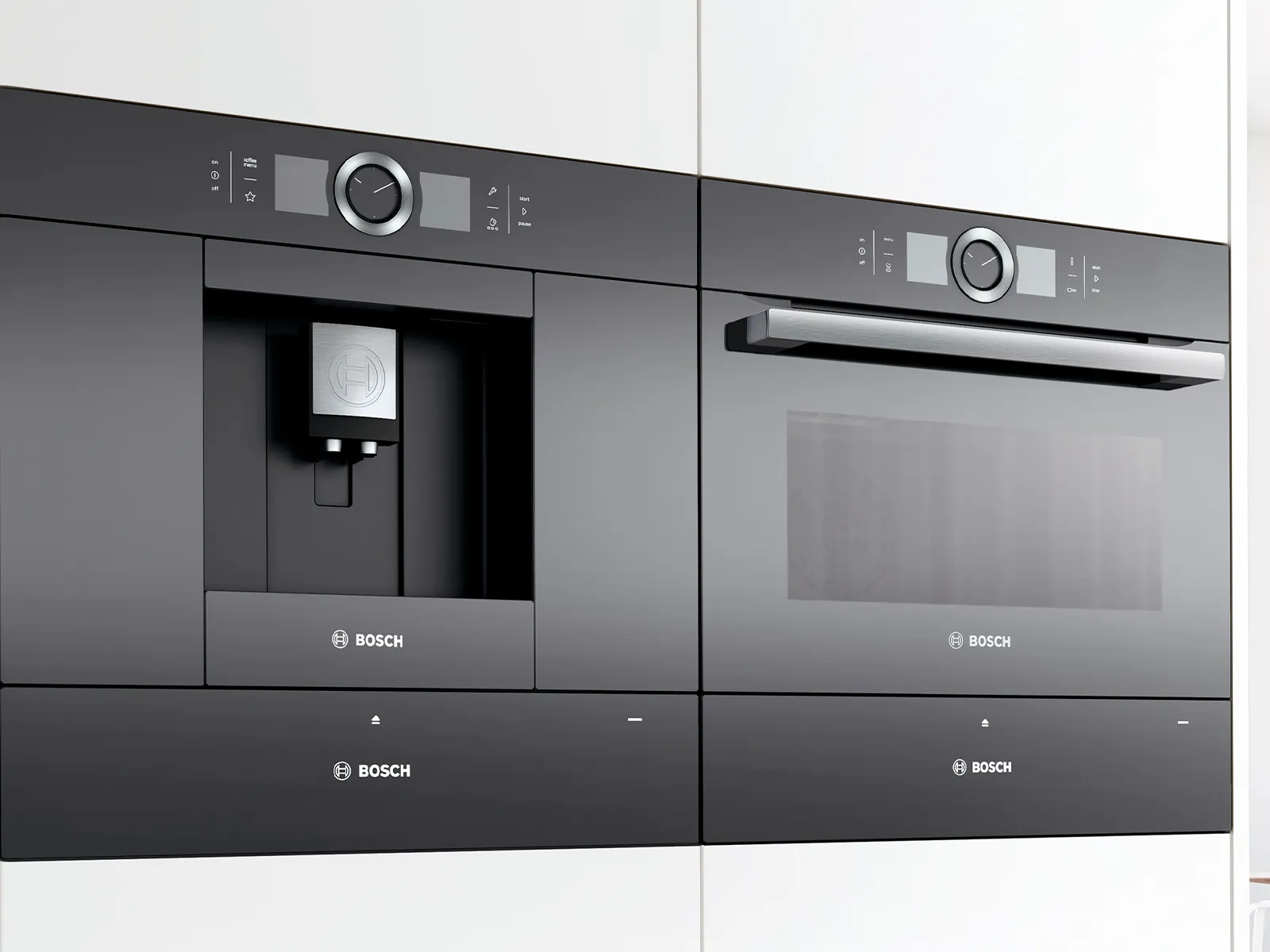 Iebūvēta kafijas mašīna blakus iebūvētai krāsnij baltā virtuvē.