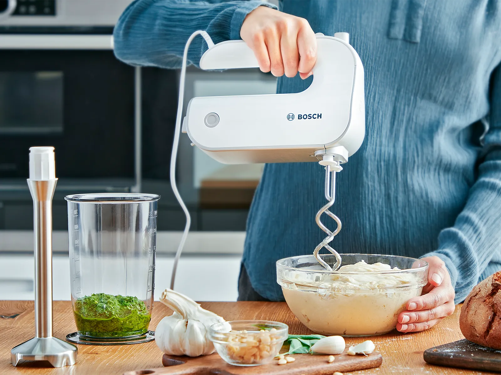 Osoba koja mijesi tijesto s ErgoMixx ručnim mikserom, pored stabljike za miješanje.