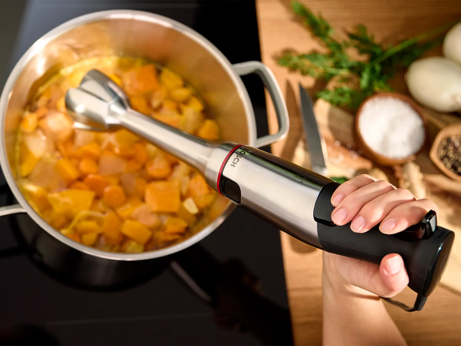 Žena koja pire povrće u kremastu juhu s Bosch ErgoMaster ručnim mikserom.