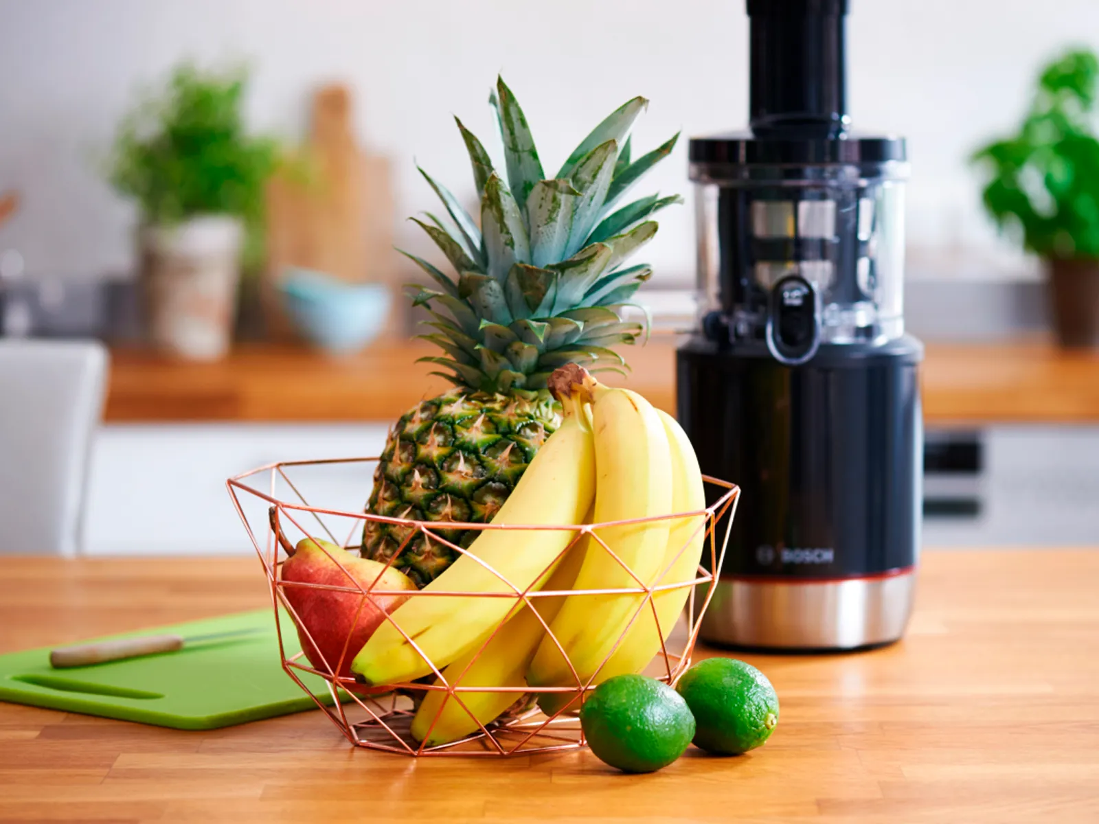 Una cesta de frutas delante de un exprimidor Bosch.