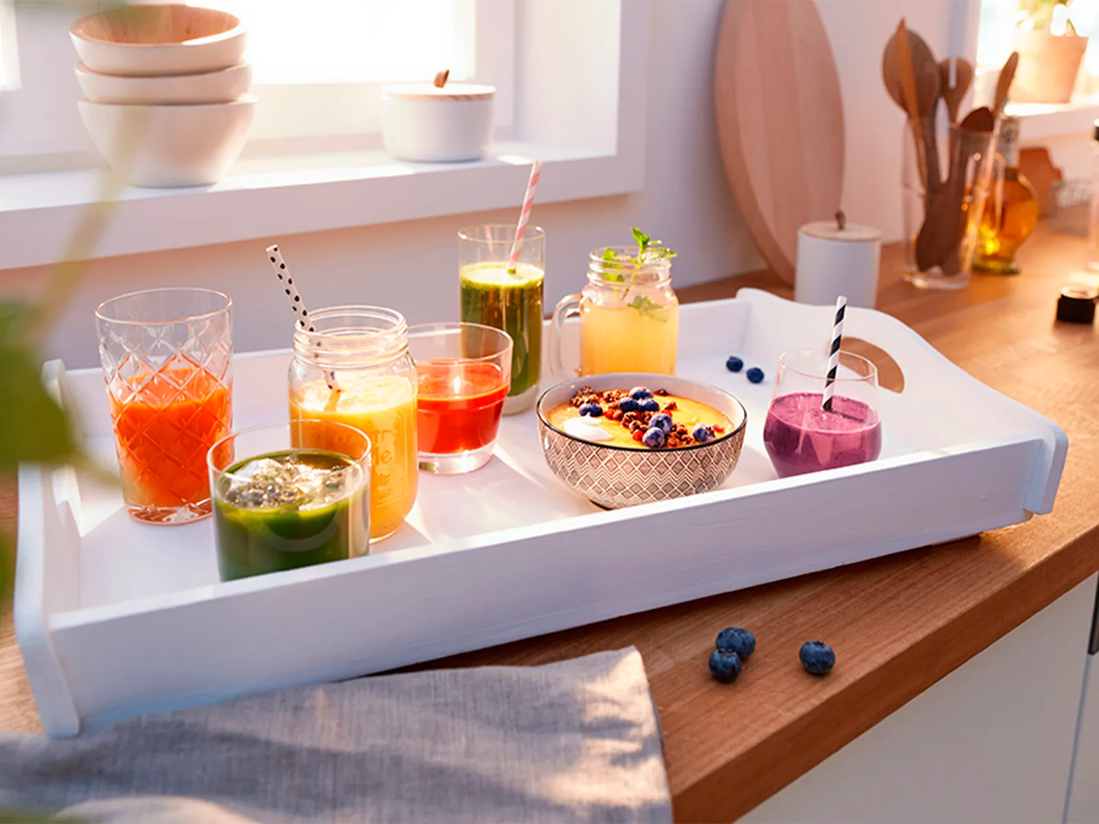 Sticlă cu suc de fructe proaspăt stors lângă o serie de preparate procesate cu maşina de tocat, inclusiv cârnaţi, salate şi falafel.