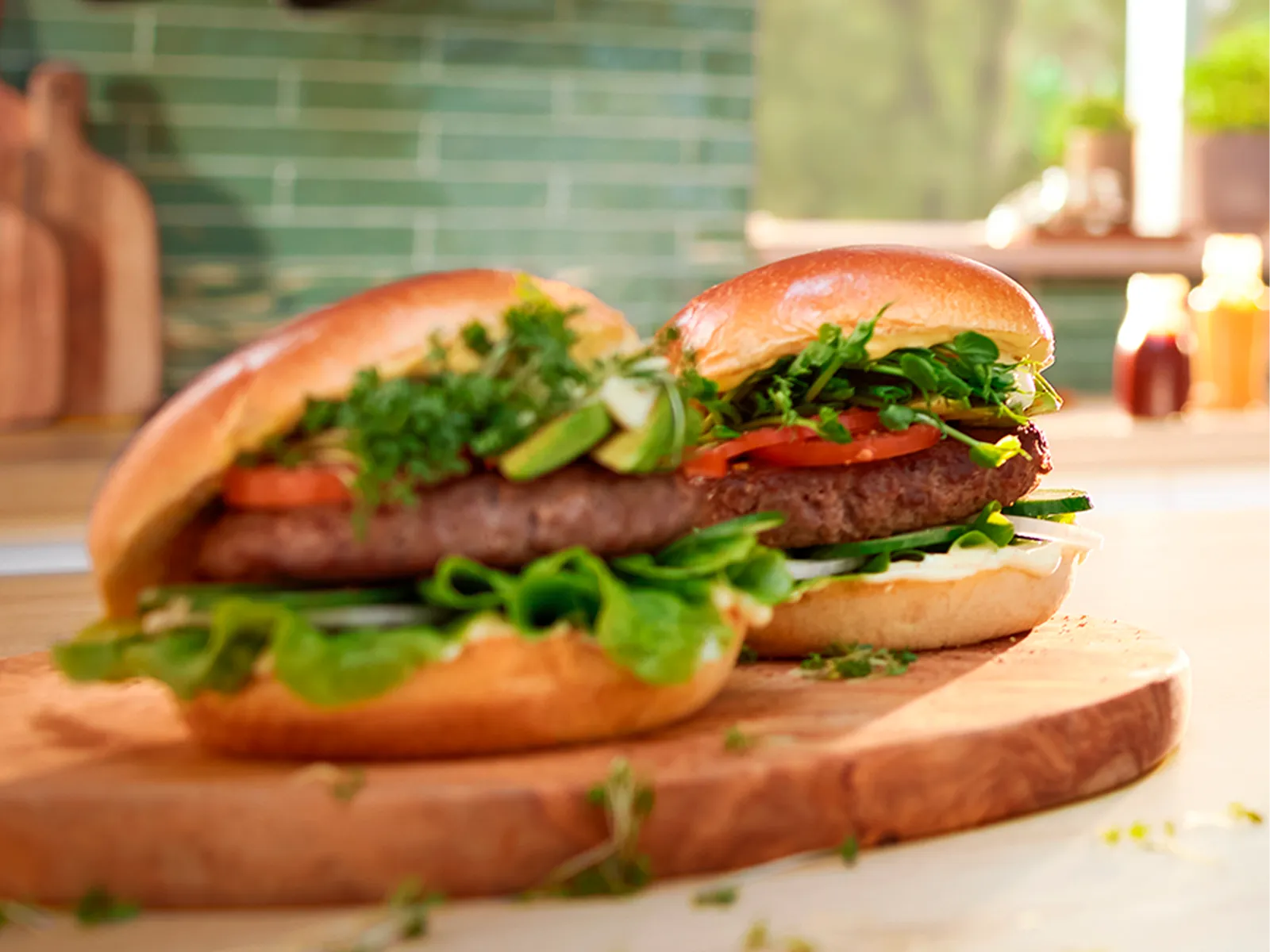 Doi burgeri în chifle pe un blat de bucătărie din lemn.