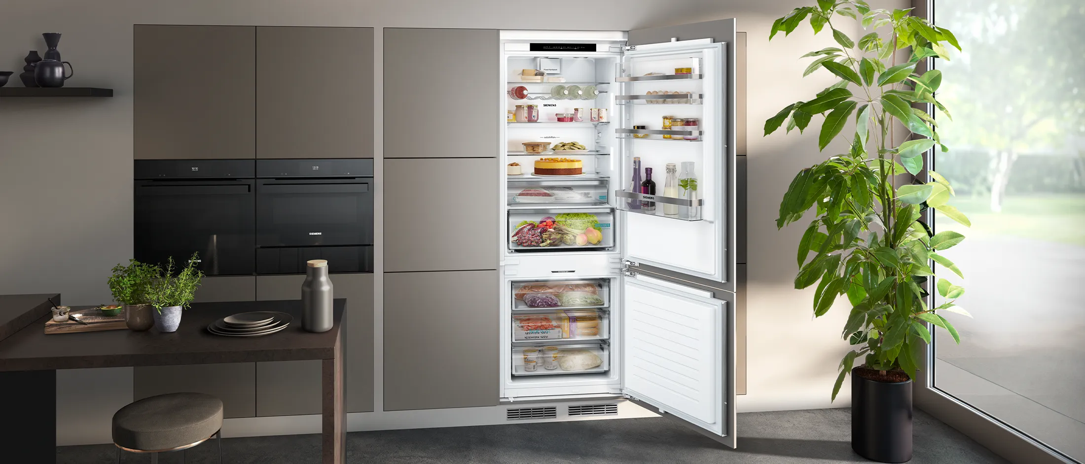 Um grande frigorífico embutido Siemens. As suas portas estão abertas e está completamente abastecido com alimentos.