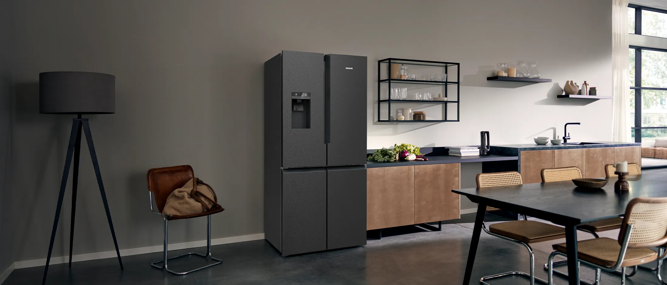 Modern kitchen with a black fridge, dining table, and a floor lamp.