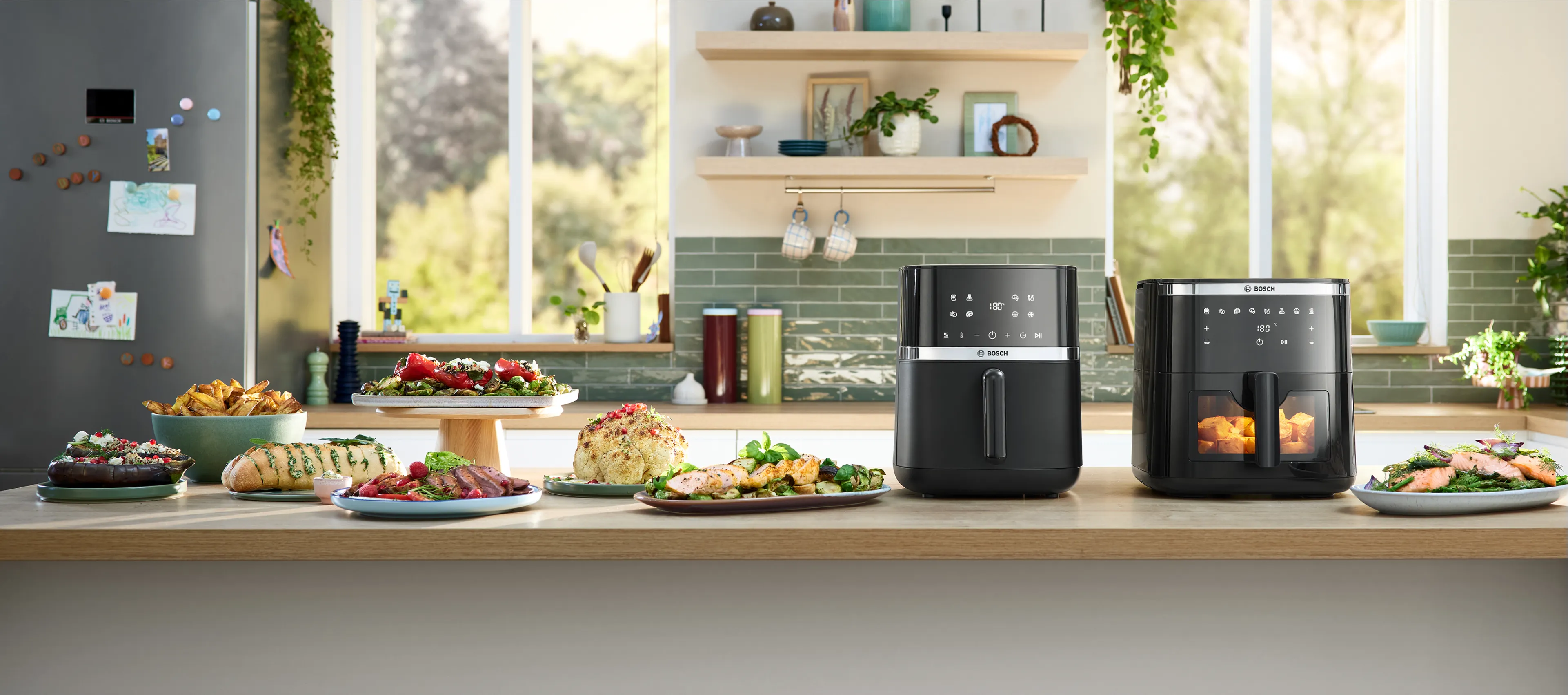 Une cuisine moderne avec deux friteuses à air noires sur un plan de travail, entourées de divers plats préparés et d'une atmosphère lumineuse et accueillante.