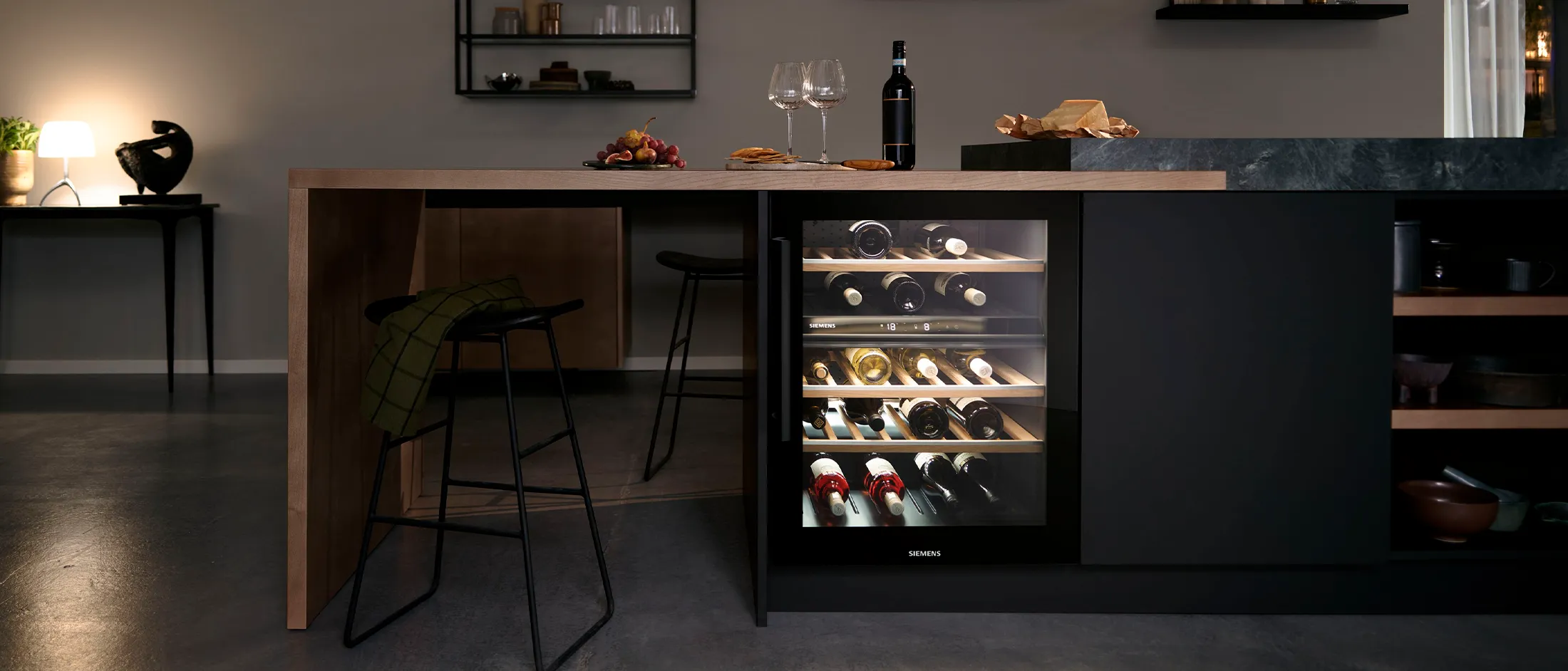 Modern kitchen with a built-in wine cooler, bar stools, and ambient lighting.