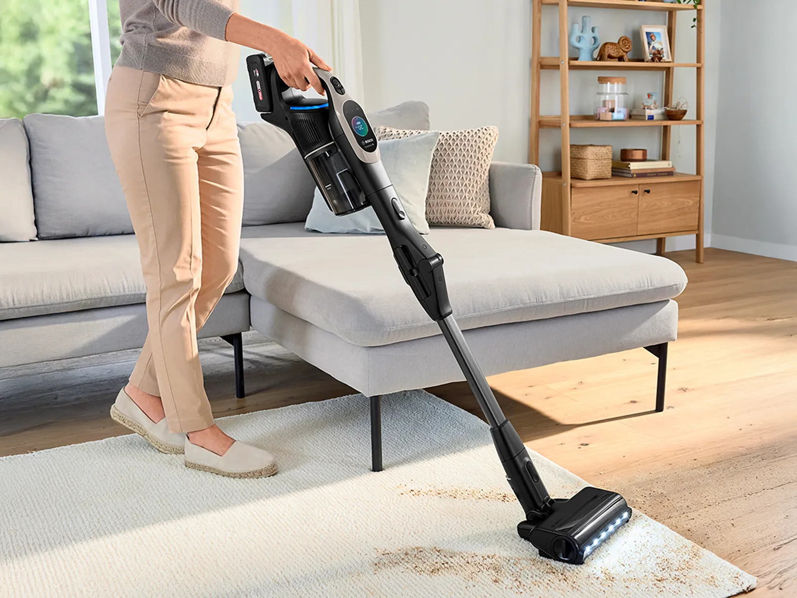 Person using Bosch Cordless Vacuum Cleaner cleaning mess in living room on gray rug