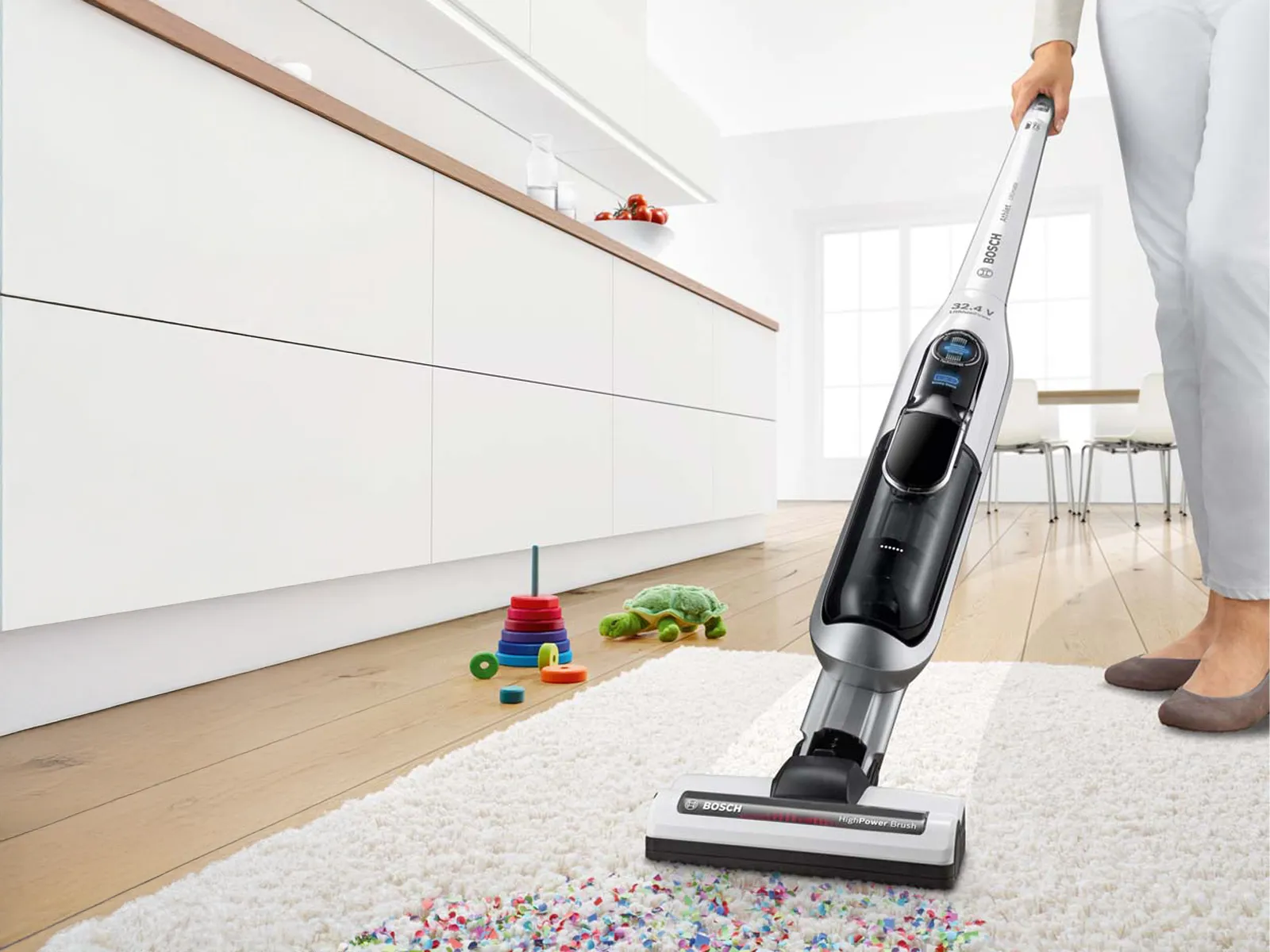 Woman vacuuming up confetti from a high-pile rug with the Athlet.