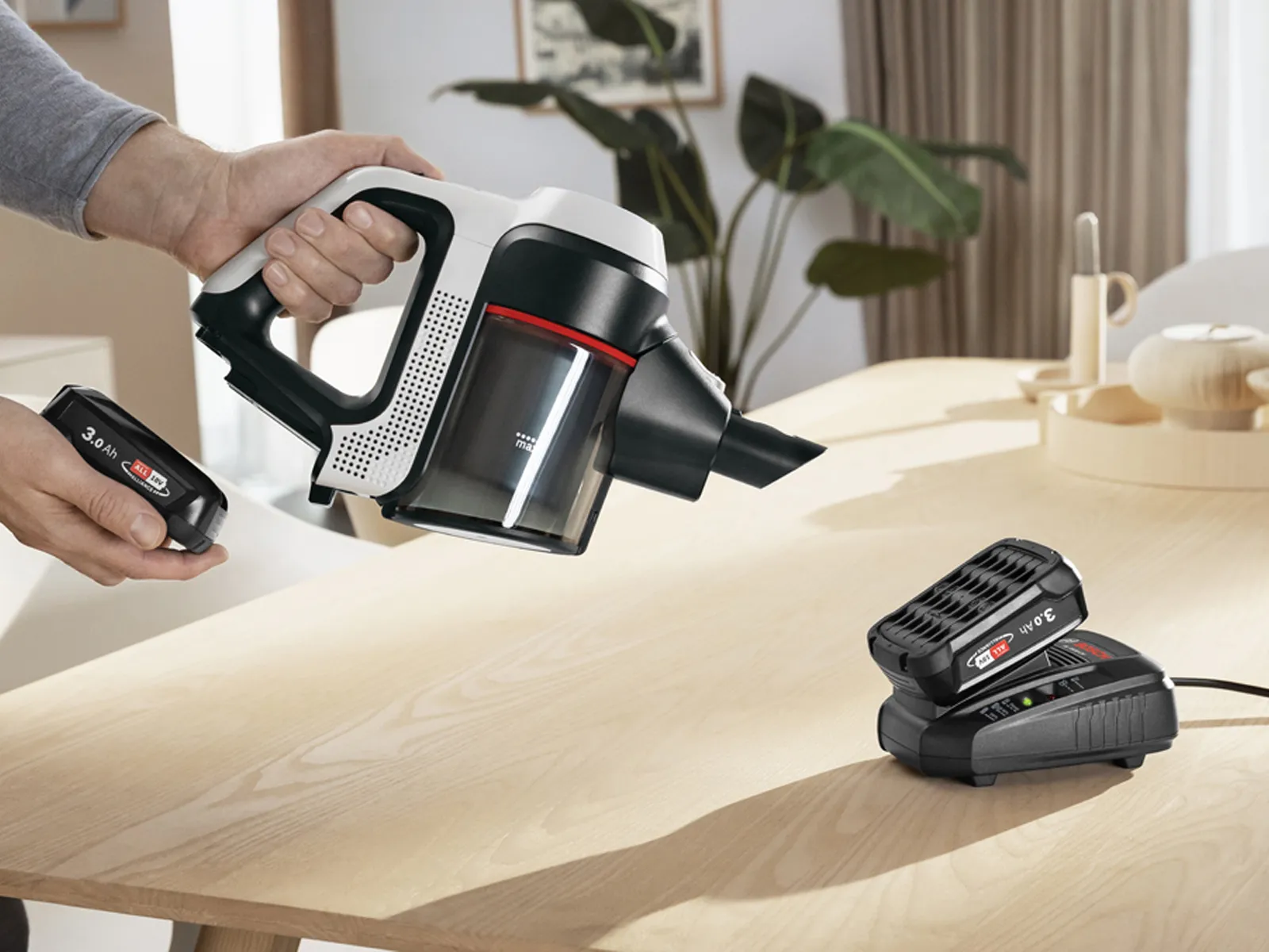 Vkládání baterie do vysavače Unlimited. Druhá baterie se nabíjí v rychlonabíječce.