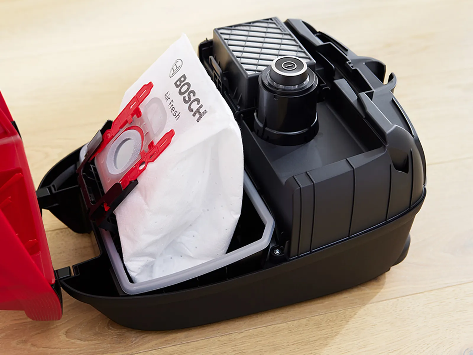 Opened vacuum cleaner showing a Bosch filter bag inside.