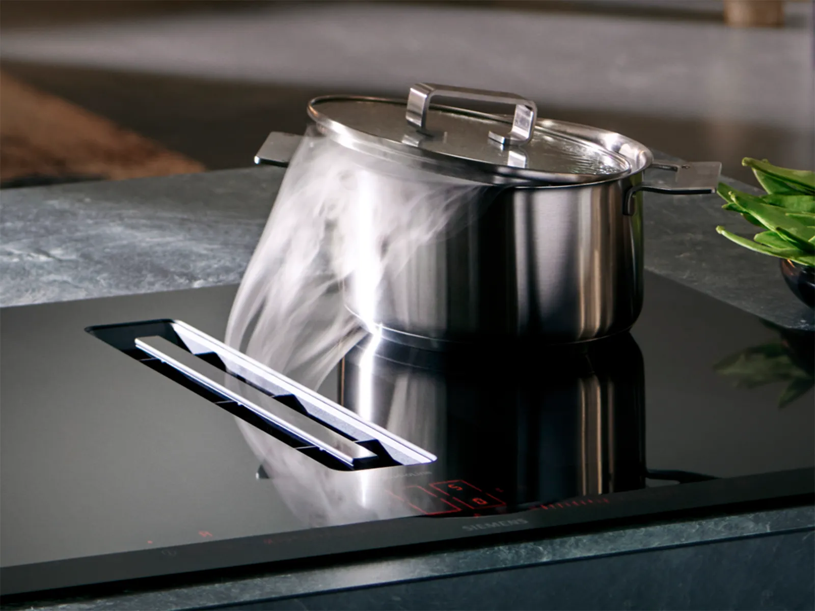 Modern Siemens induction cooktop with an integrated ventilation system, capturing steam from a pot.