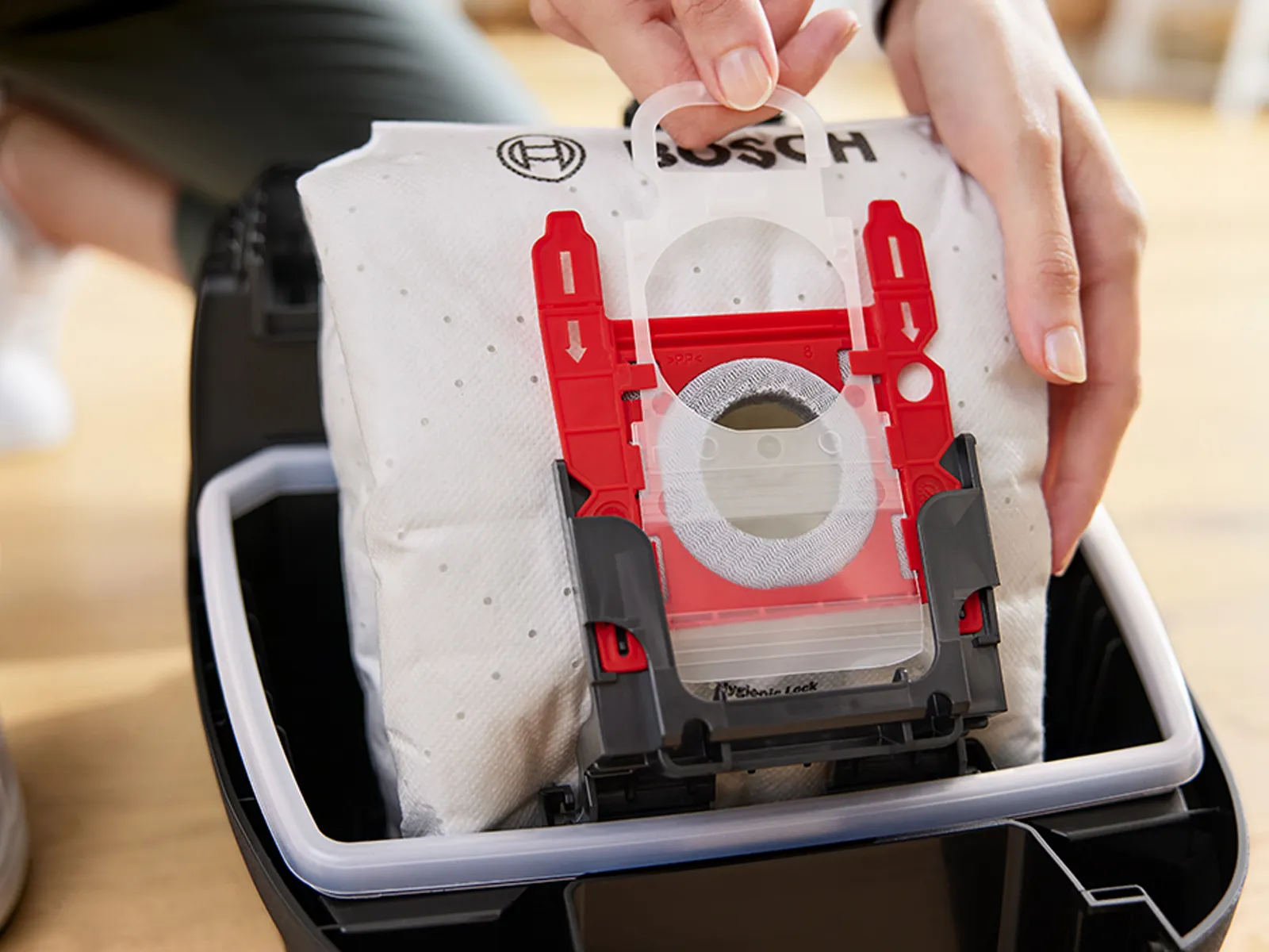 A hand disposes of a sealed vacuum cleaner dust bag.