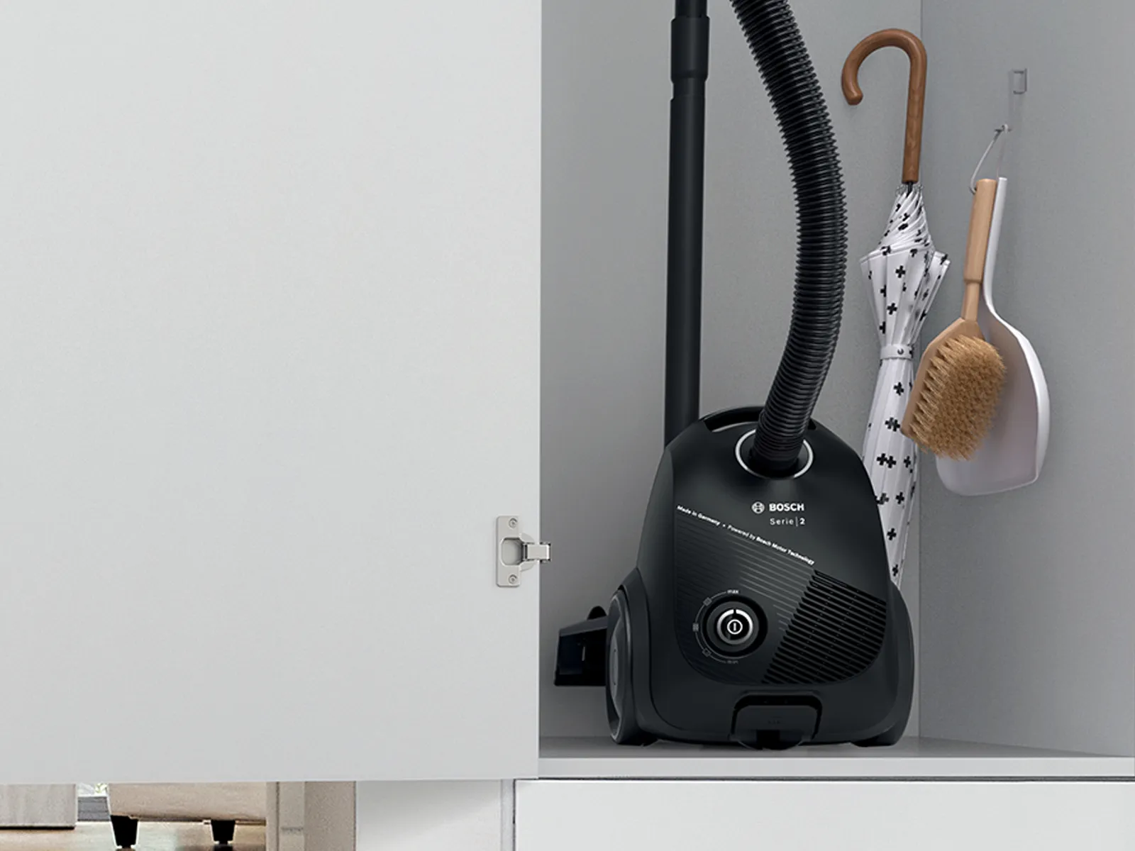 A Bosch super-compact bagged vacuum cleaner easily fits in a cupboard together with an umbrella as well as a dust pan and brush set.