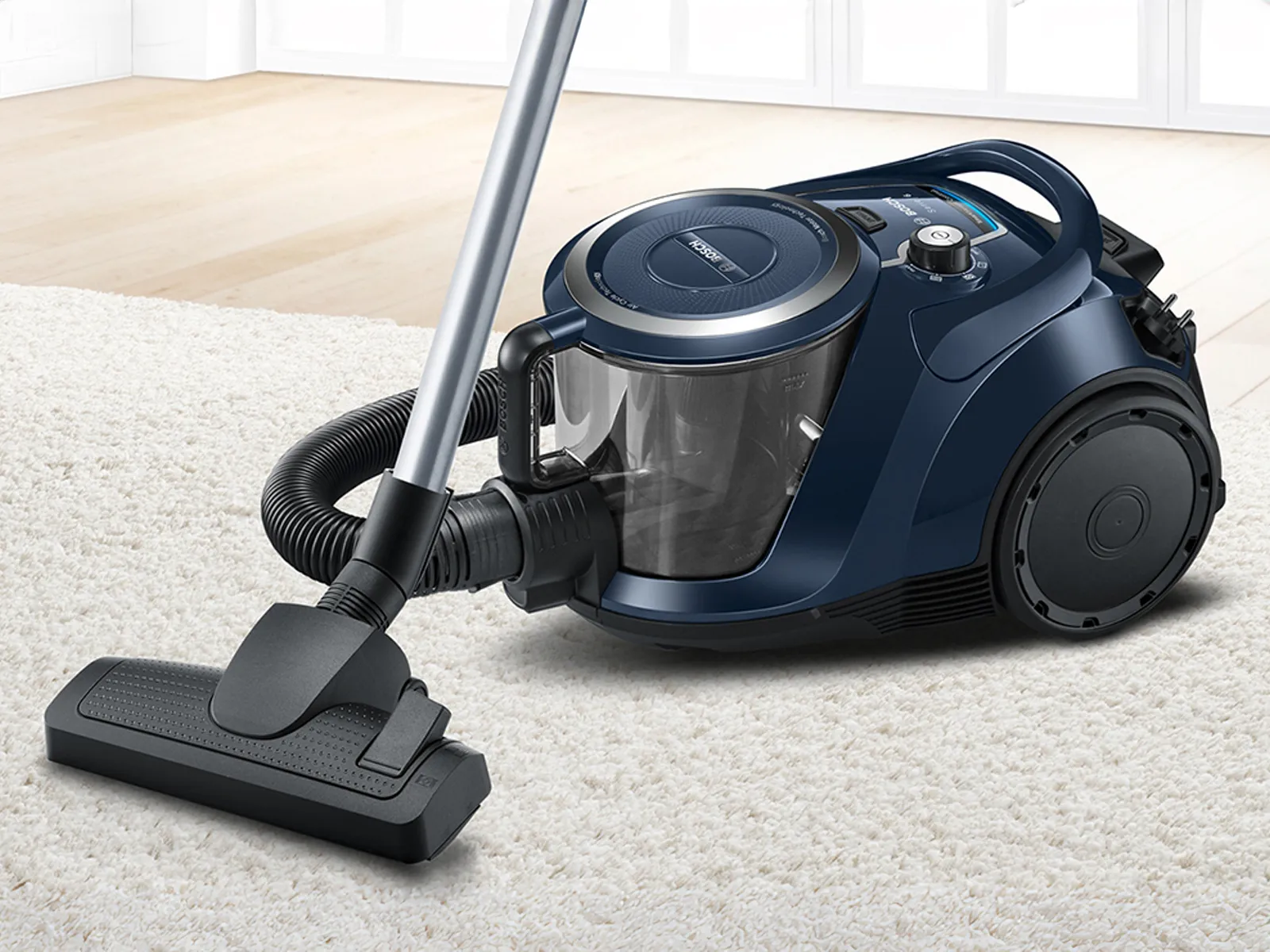 A dark blue bagless vacuum on a living room rug.