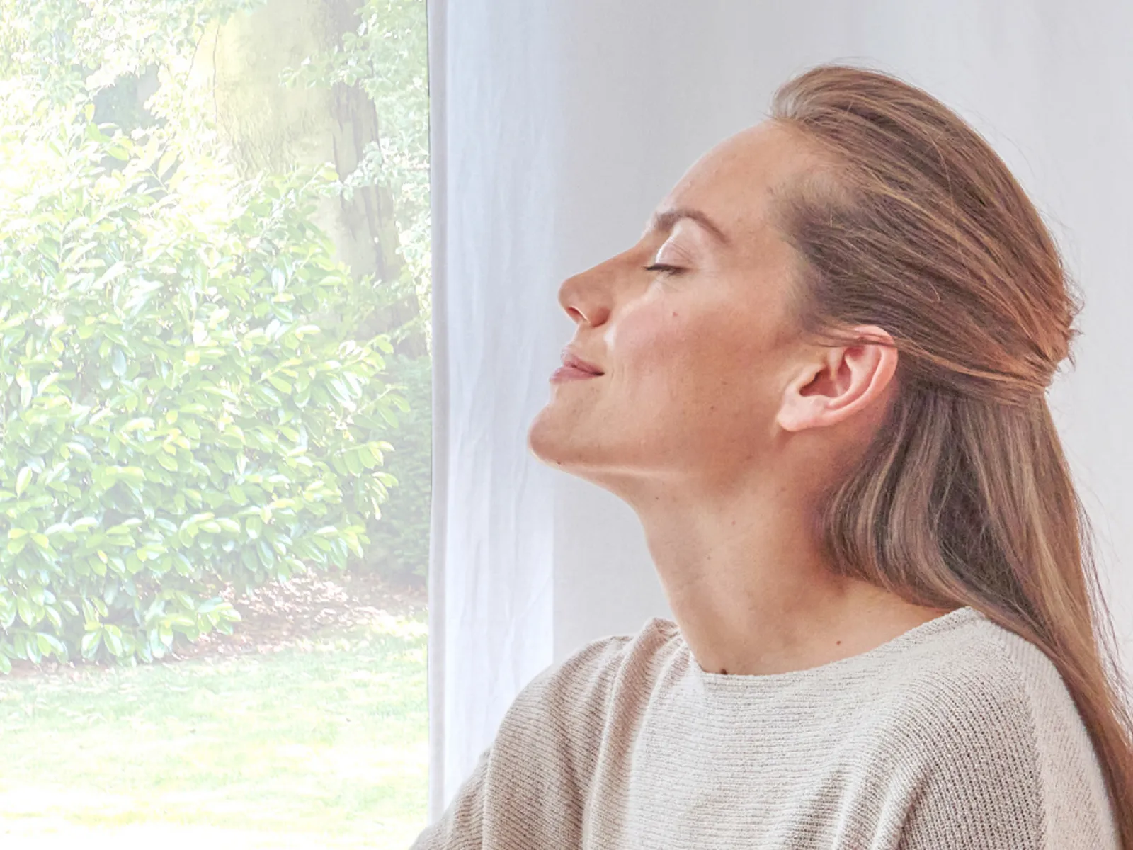 A woman with her eyes closed inhales deeply and pleasurably.