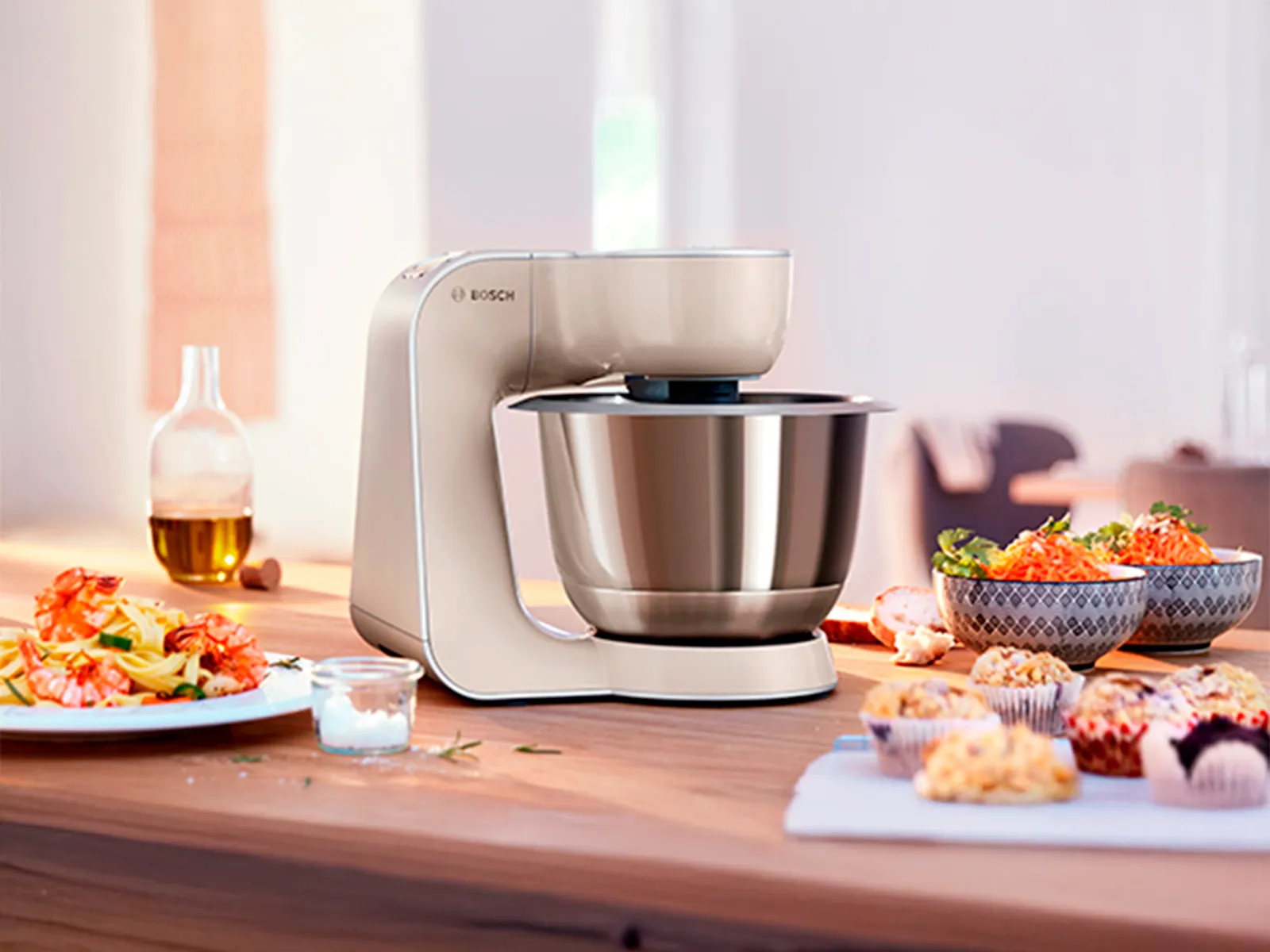 Vaalea Bosch-yleiskone keittiön pöydällä. Ympärillä monenlaisia ruokia.