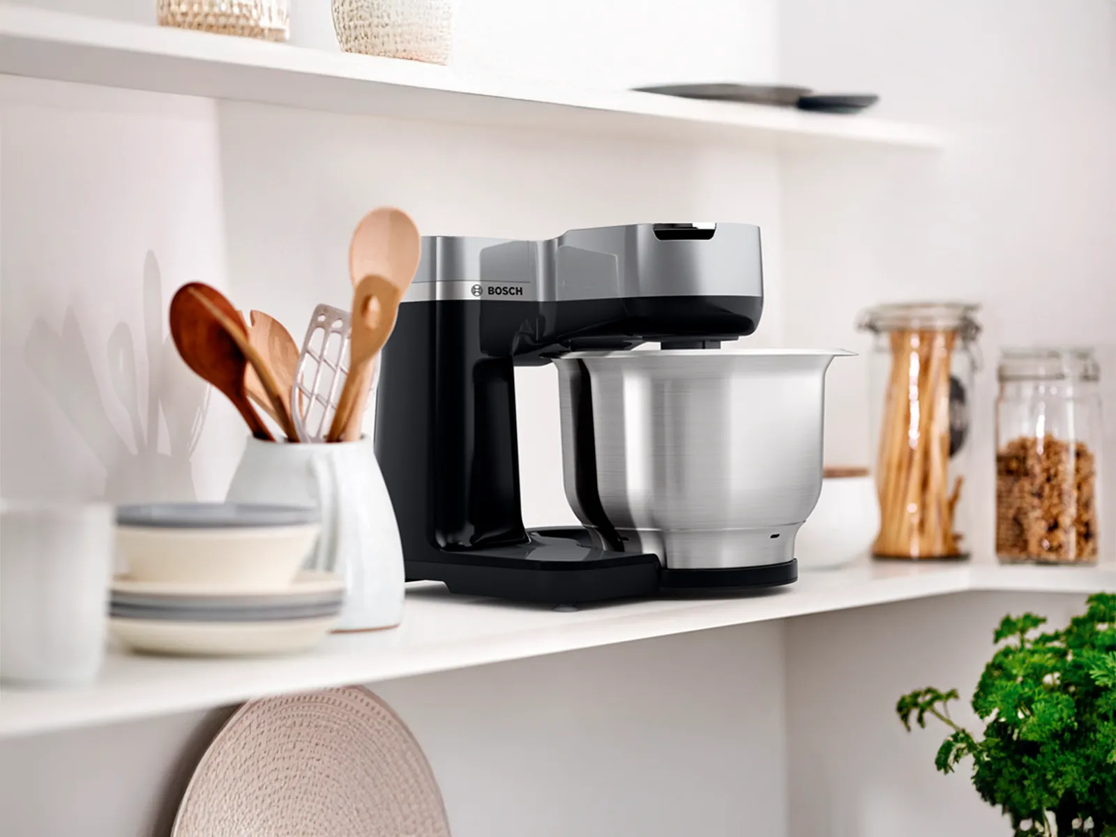 Une cuisine avec un robot sur socle Bosch et divers articles disposés sur des étagères