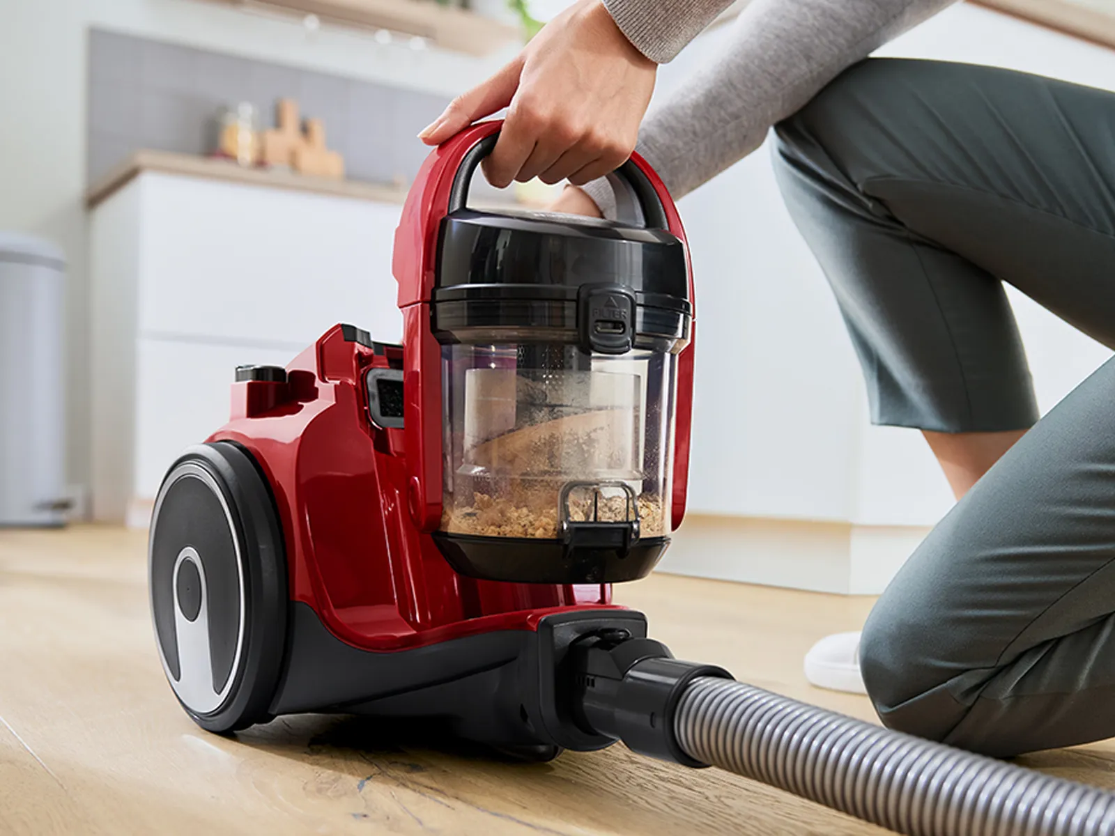 A person lifts the dust box out of a bagless canister vacuum.