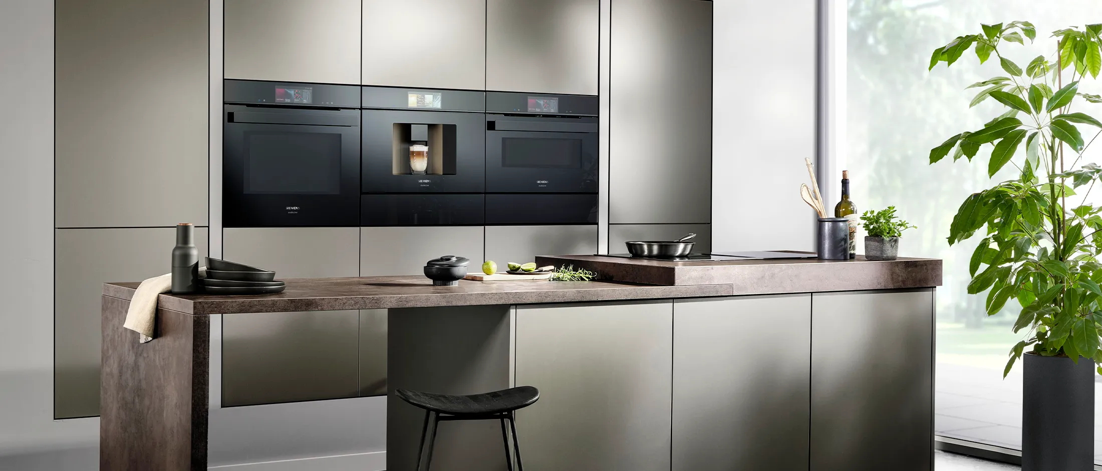 Cozinha moderna com electrodomésticos pretos elegantes, armários escuros e uma bancada de madeira.