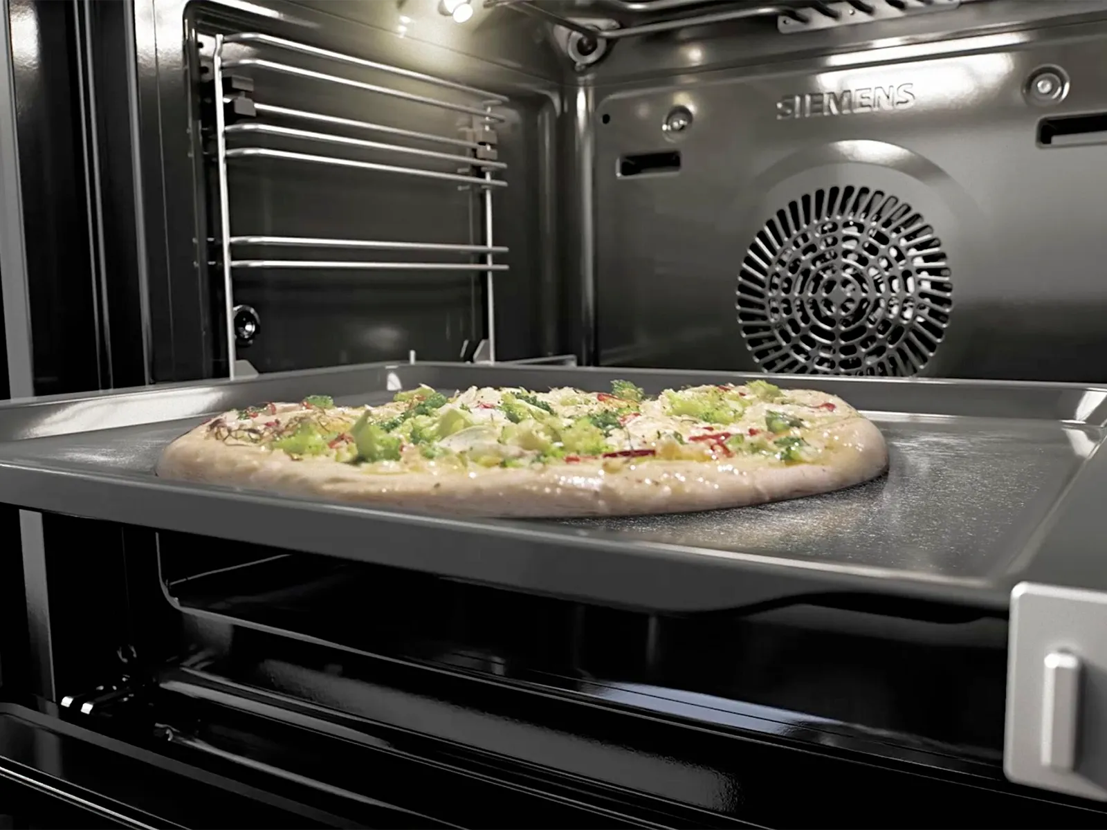 Uncooked pizza on a tray inside a Siemens oven.