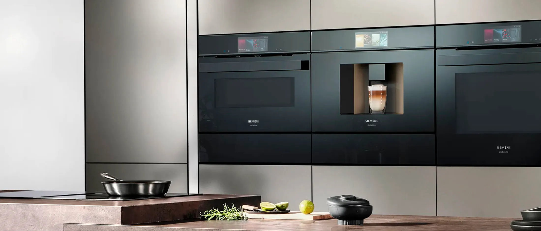 Eletrodomésticos embutidos em preto da Siemens, incluindo fornos e uma máquina de café, para uma experiência de cozinhar moderna e integrada.