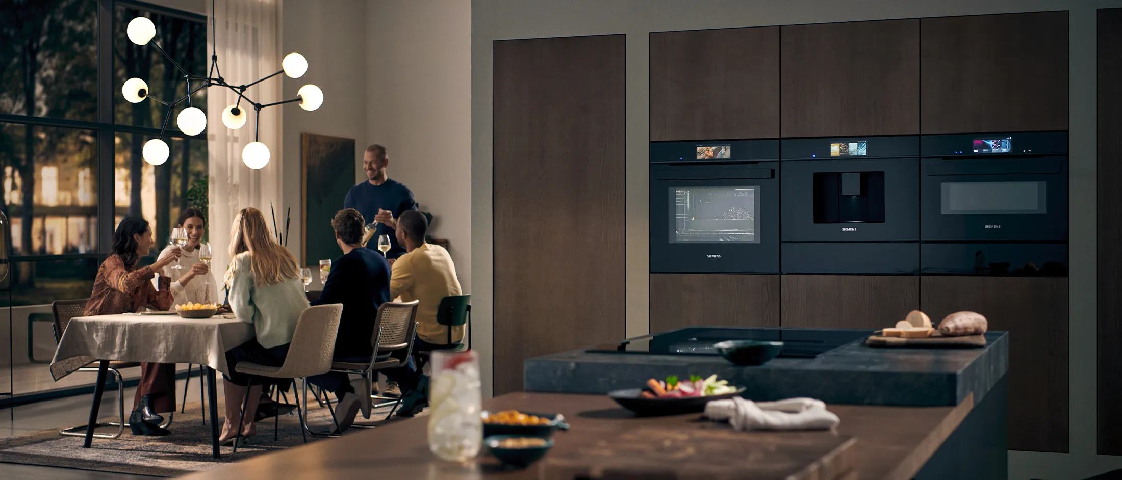 Modern kitchen with Siemens built-in appliances, as friends gather for a stylish and cozy dinner.