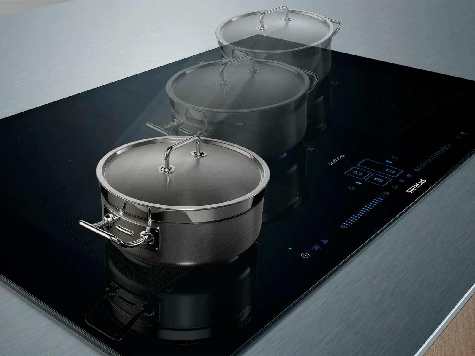 Tre gryder i rustfrit stål på en moderne induktionskogeplade med touch display.