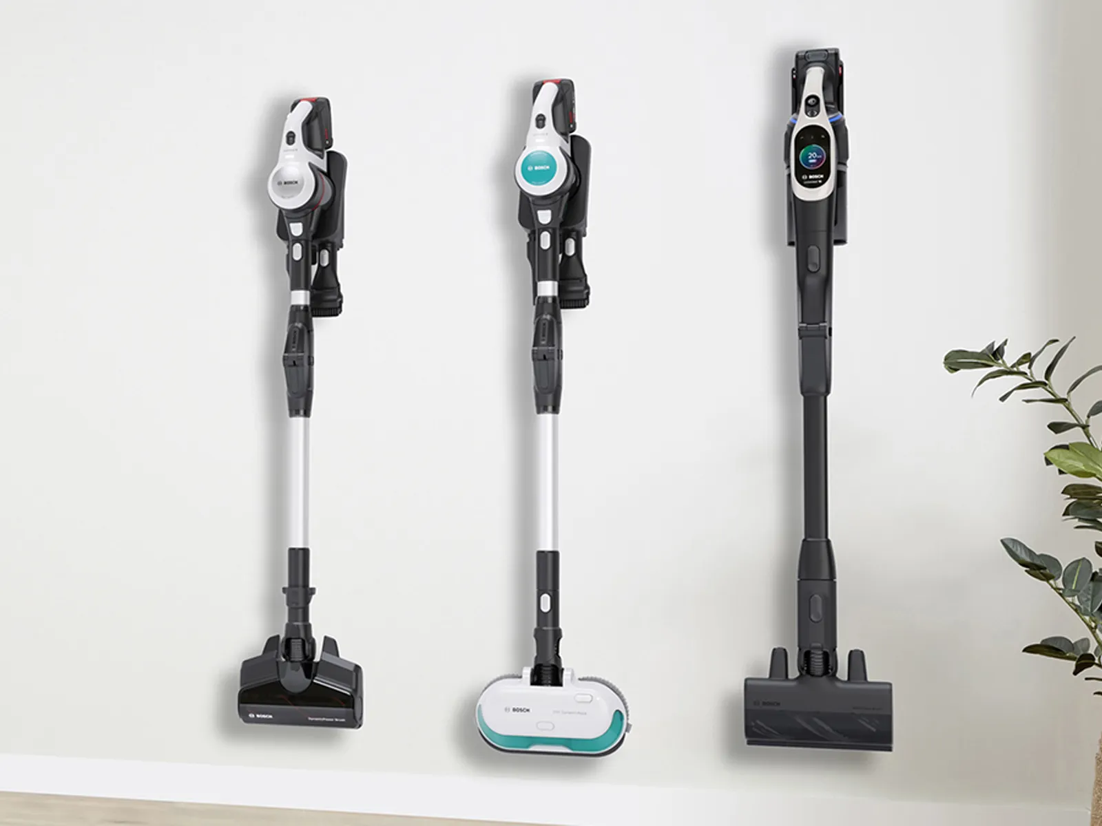 Drei kabellose Staubsauger hängen an der Wand in ihren Ladestationen.