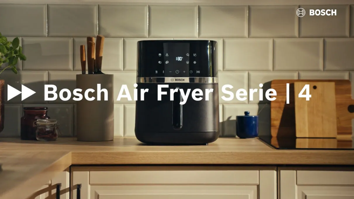Zwarte Bosch Air fryer (Serie 4) op een houten aanrecht voor een witte tegelachterwand; links een messenhouder en potjes, rechts snijplanken, met witte tekst 'Bosch Air Fryer Serie | 4' en Bosch-logo in de hoek.