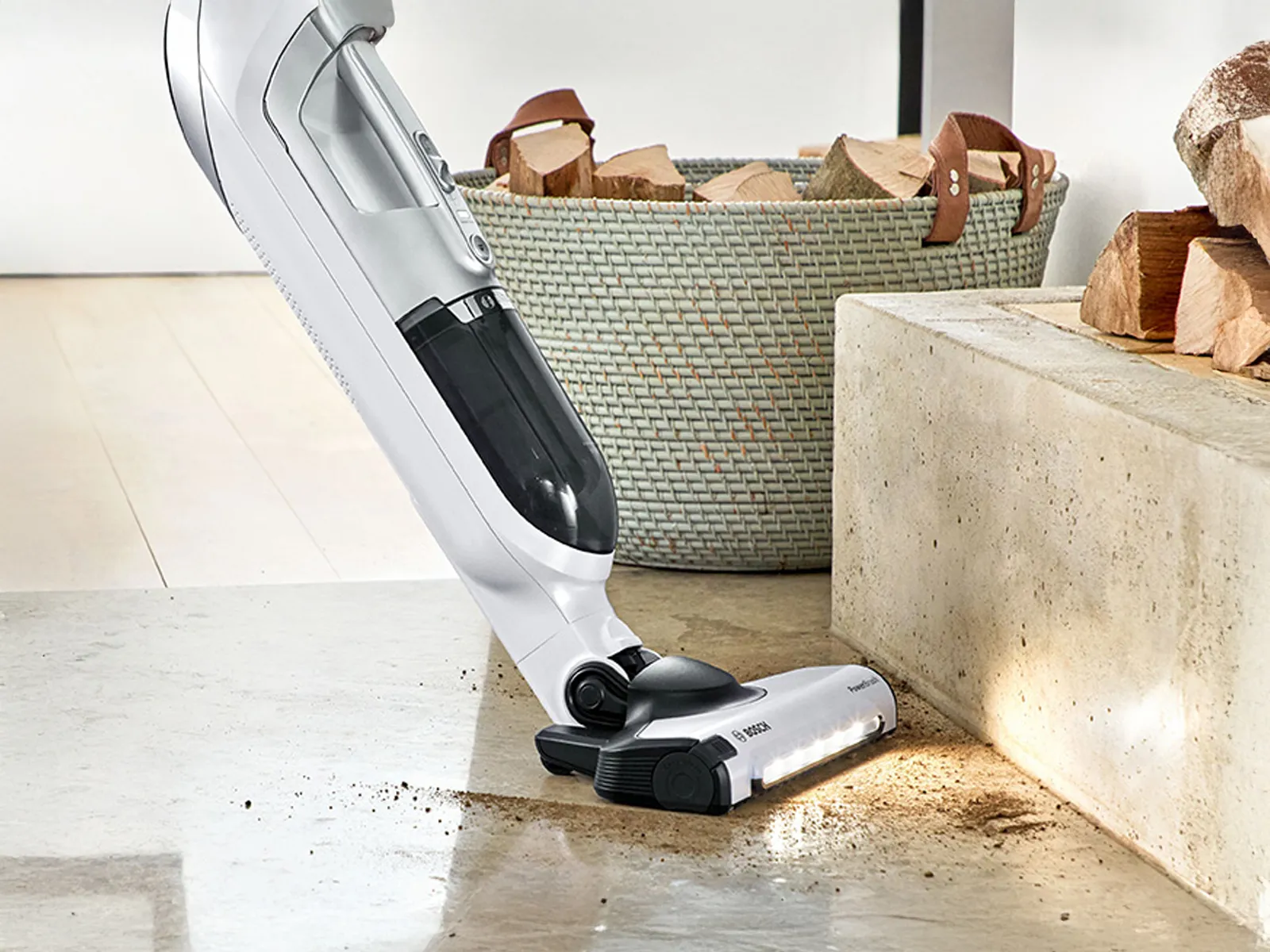 Eine Frau saugt Konfetti vom Teppich mit dem kabellosen Staubsauger Bosch Flexxo.