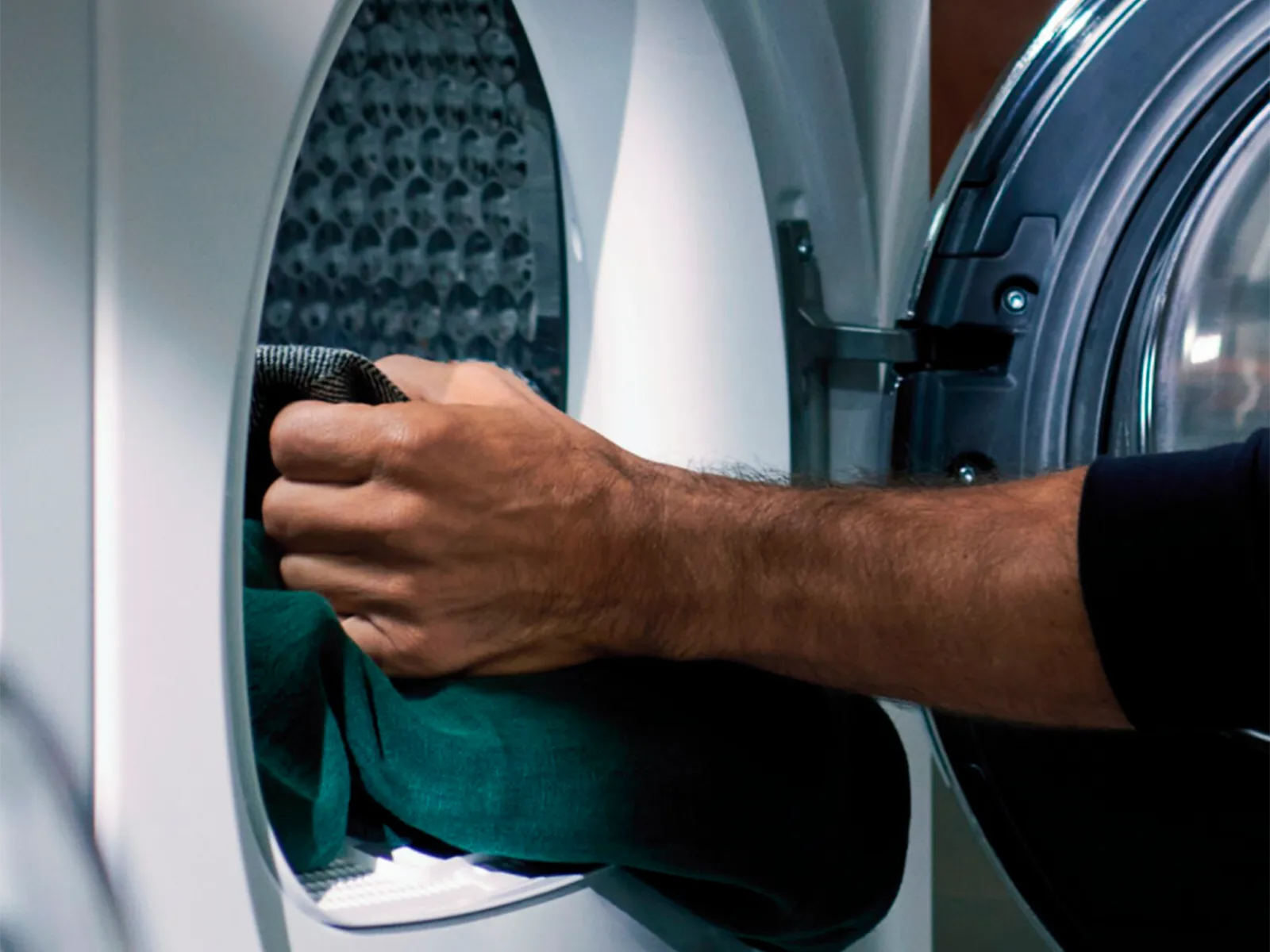 Person som lägger in kläder i en frontmatad tvättmaskin.