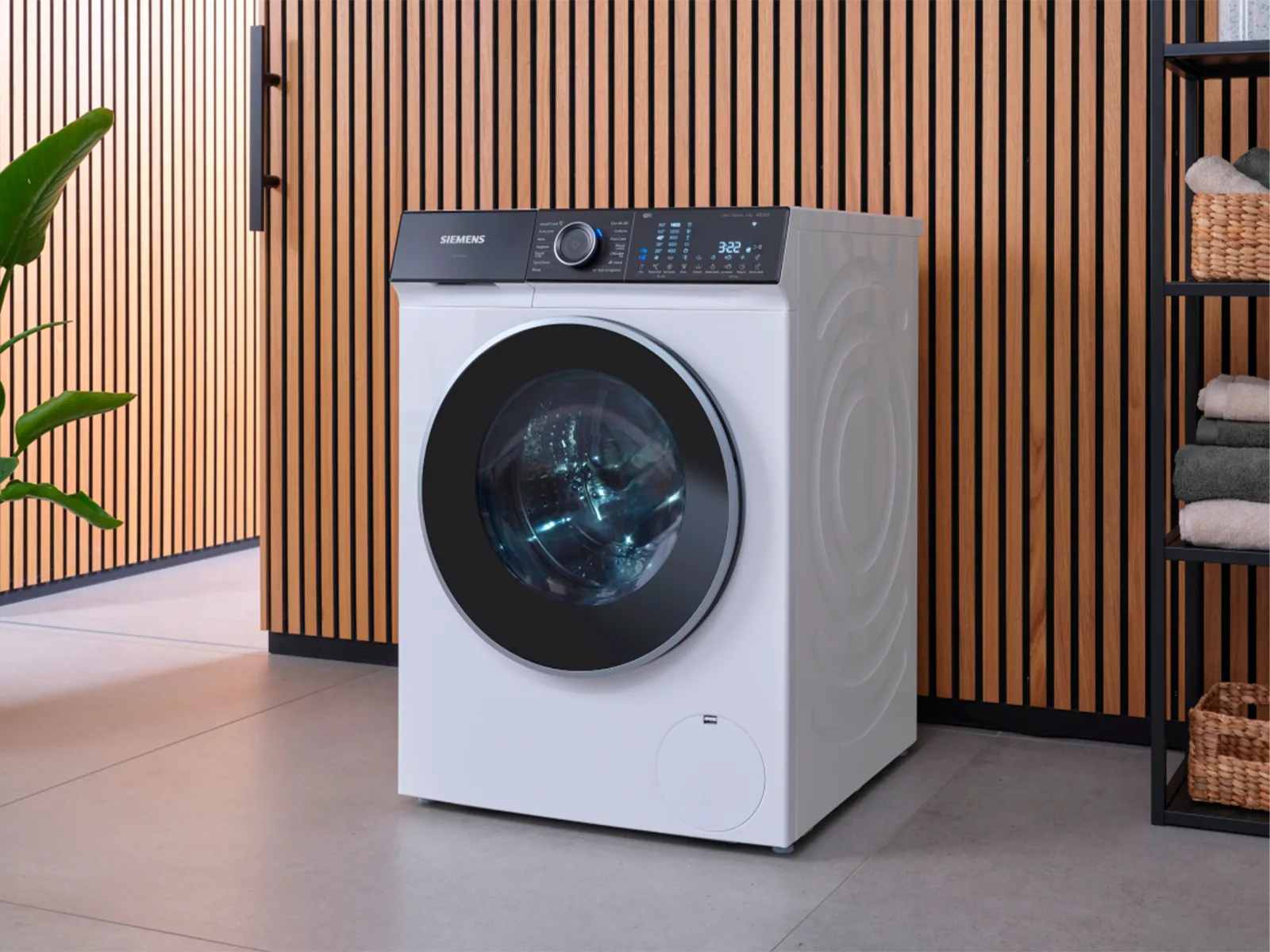 En moderne vaskemaskine i et rum med træbeklædte vægge og en reol med håndklæder.