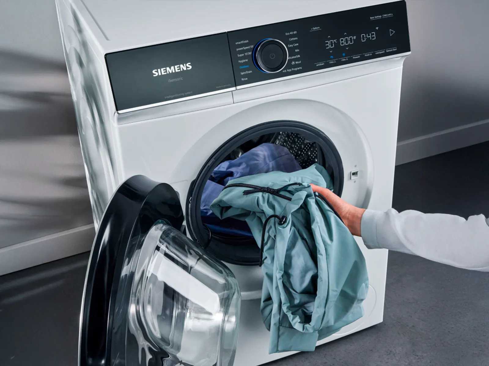 Pessoa a verter detergente numa máquina de lavar.