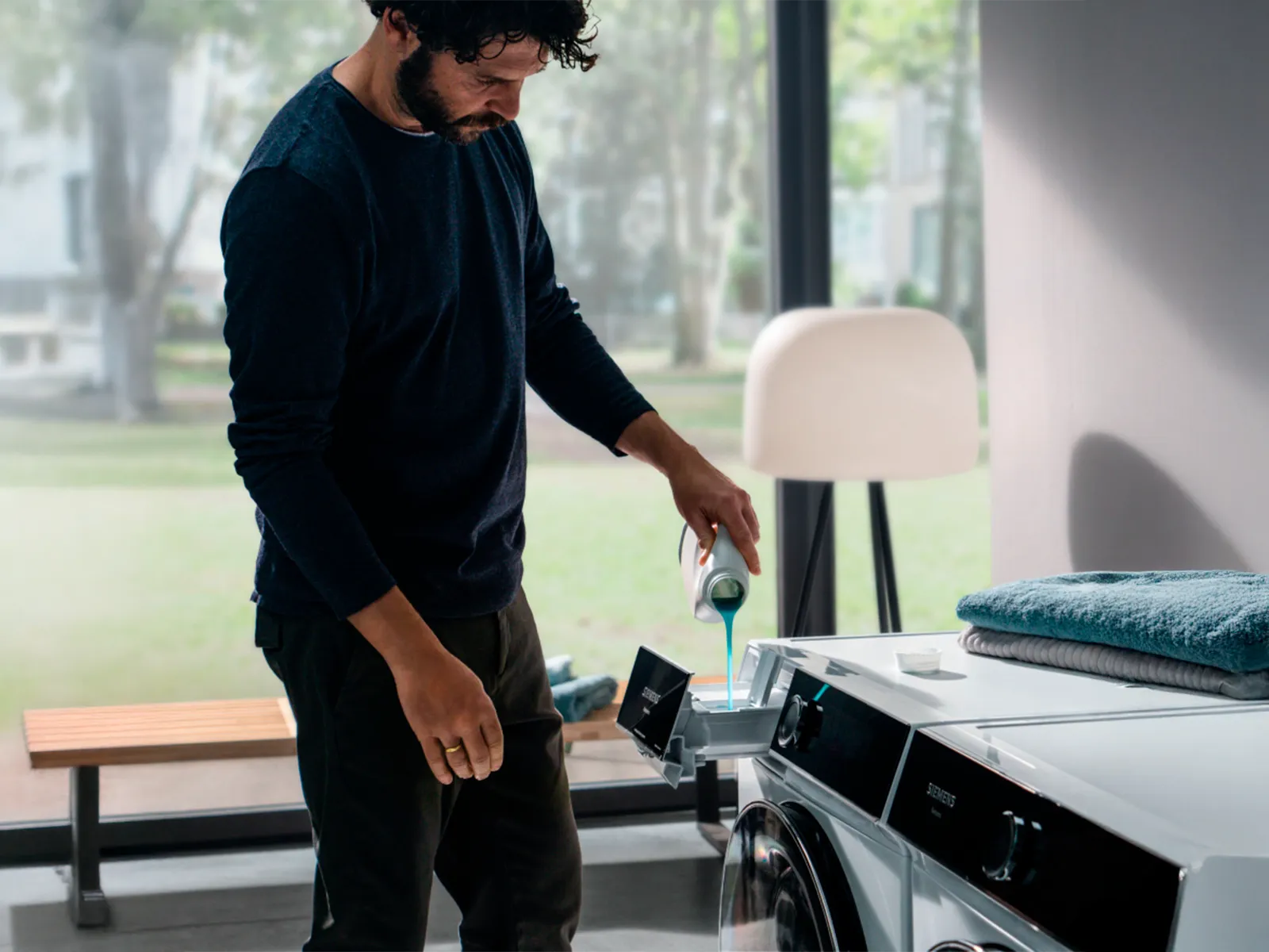 Pessoa a verter detergente numa máquina de lavar.