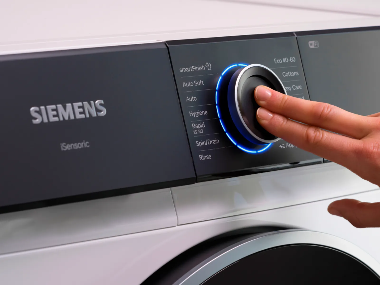 Mão a ajustar um botão no painel de controlo de uma máquina de lavar Siemens.