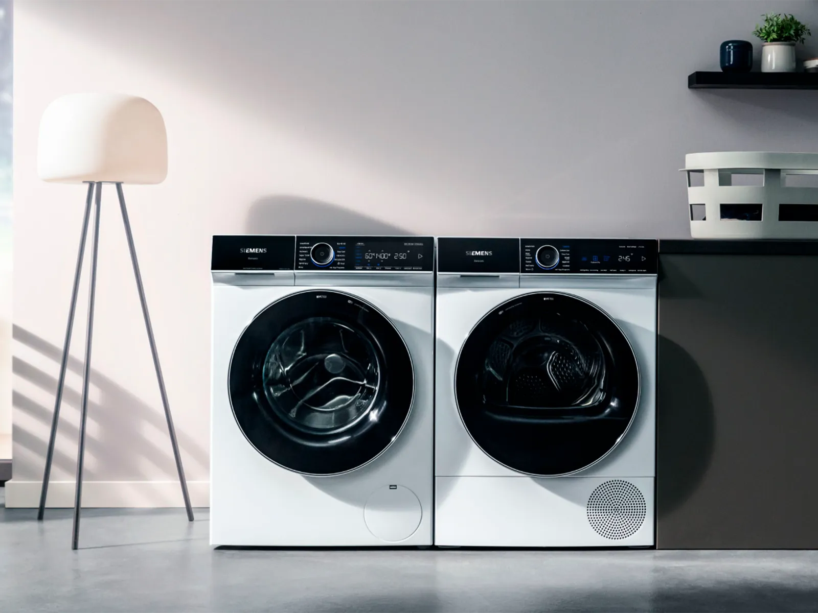 Uma lavandaria moderna com uma máquina de lavar e uma secadora, uma luminária e uma prateleira com plantas.