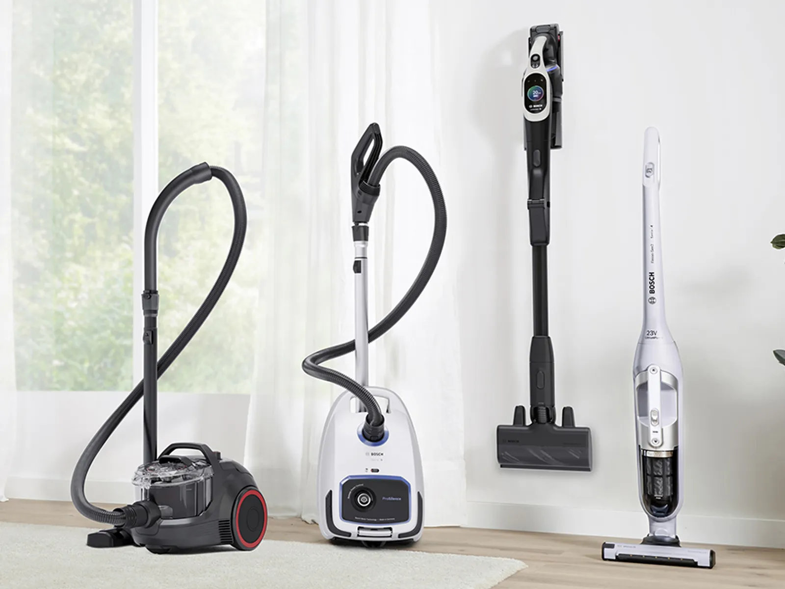 Drei verschiedene Arten von Staubsaugern auf dem Boden eines Raumes.