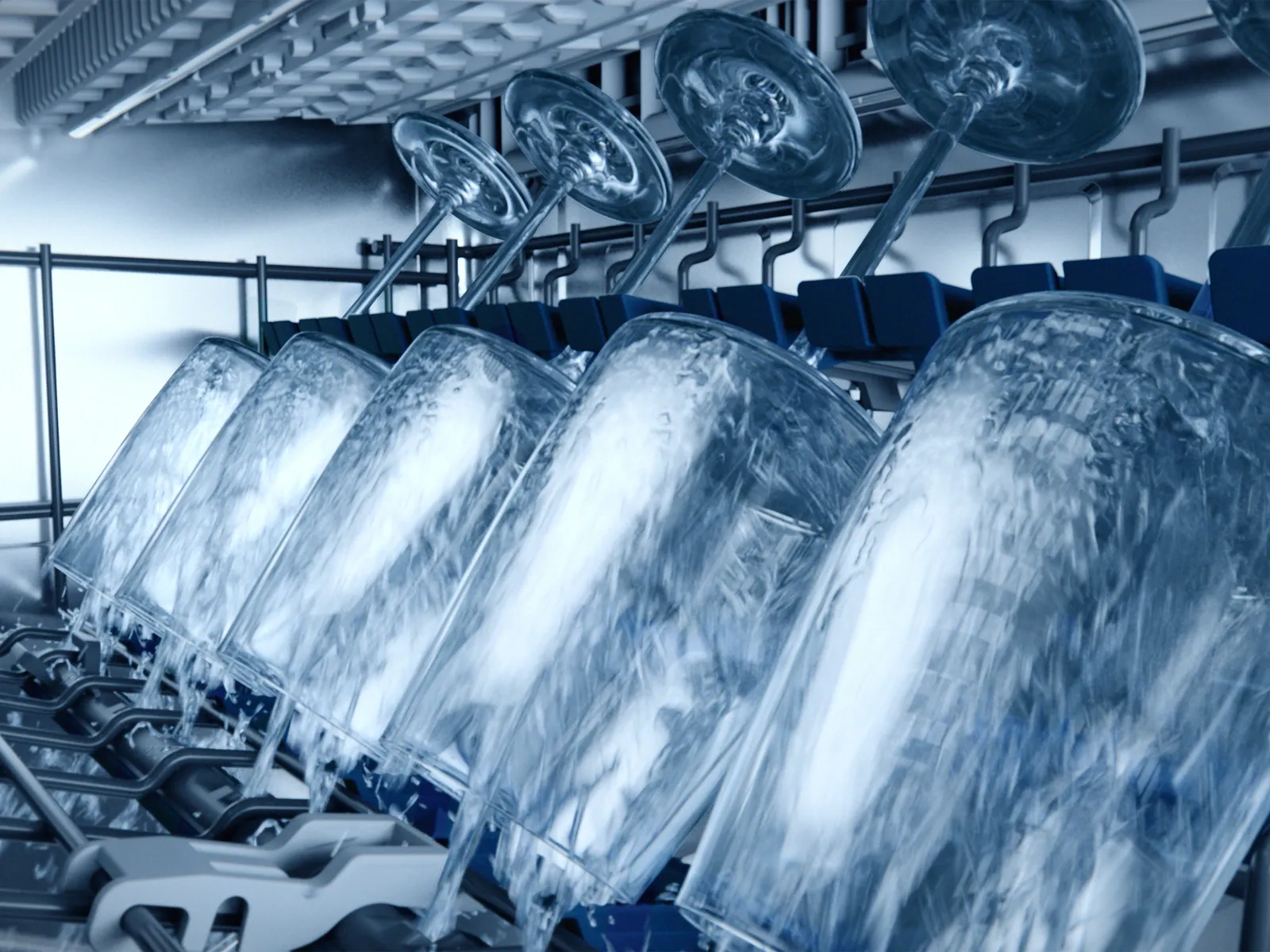 Wine glasses upside down in a dishwasher rack being washed.