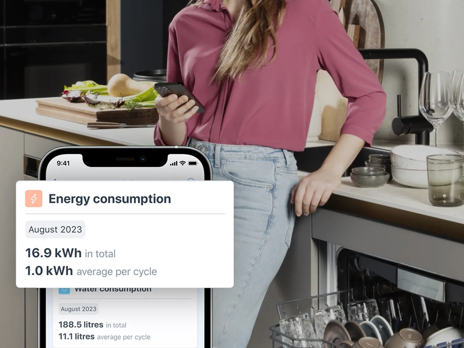 Person, der holder en telefon med energiforbrugsstatistikker i et køkken.