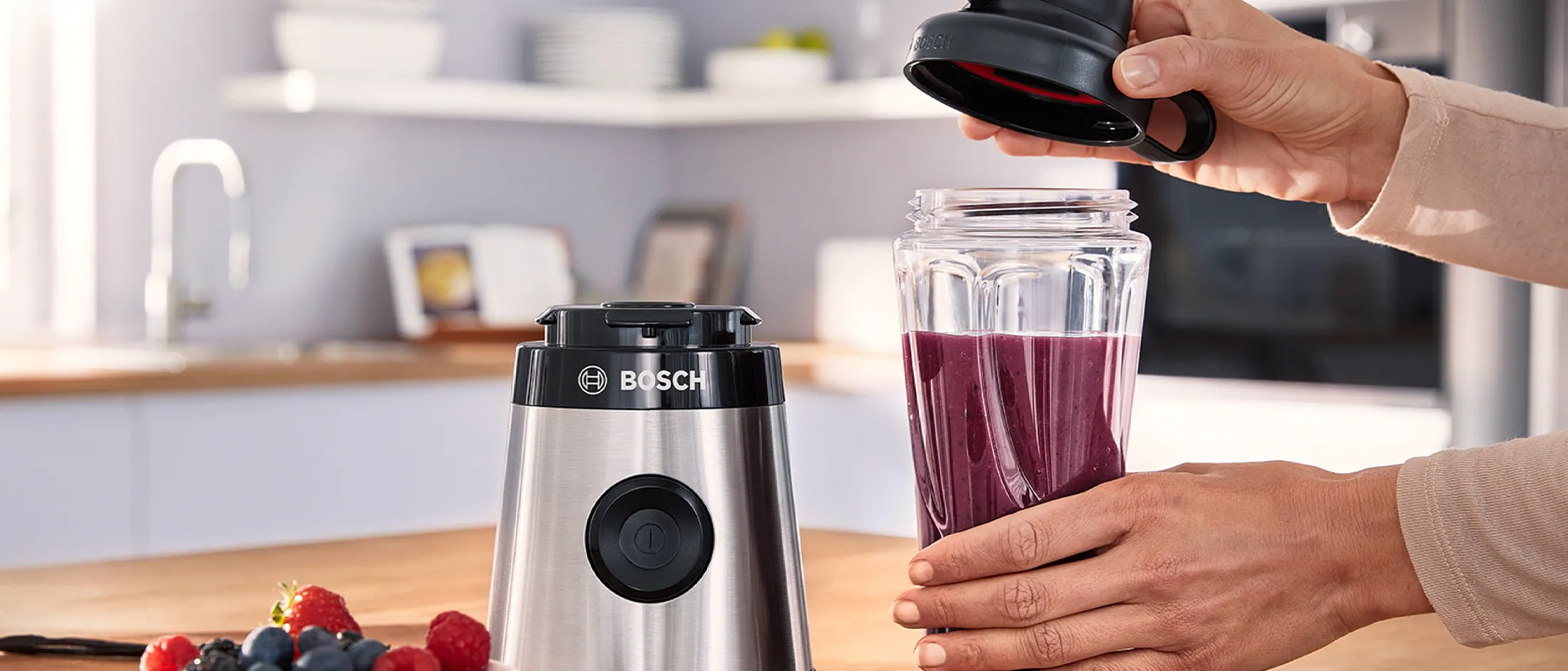 A mulher está abrindo o liquidificador mini VitaPower Serie 2 da Bosch.